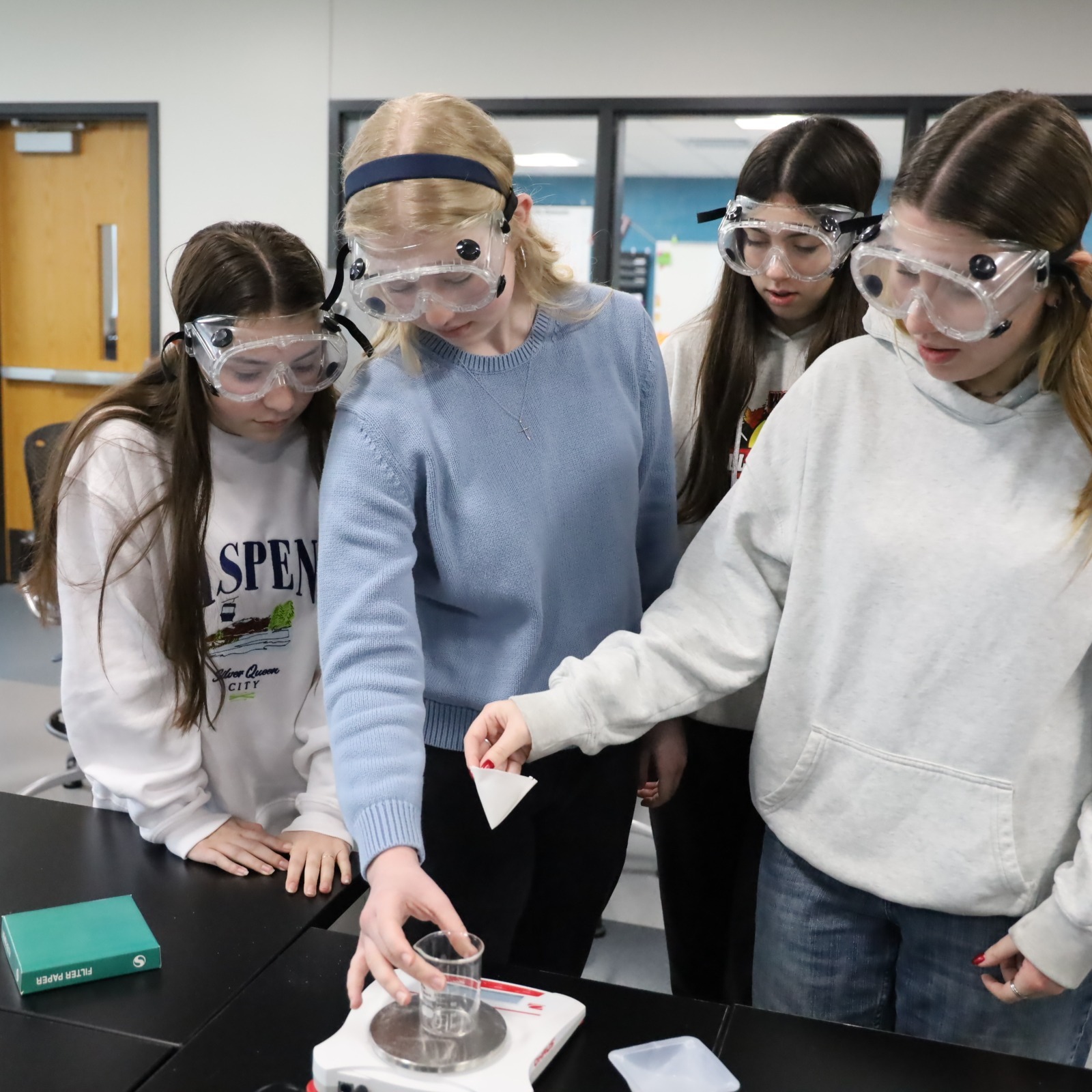 Chemistry experiment Four students together wearing goggles