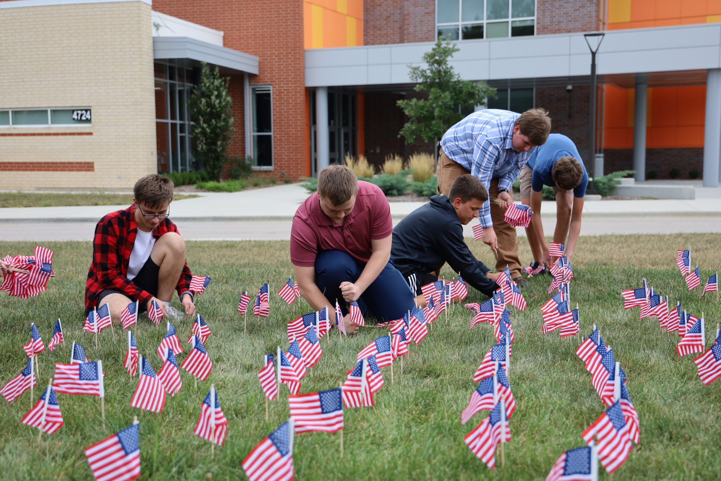 Students setting up many small American flags in the grass