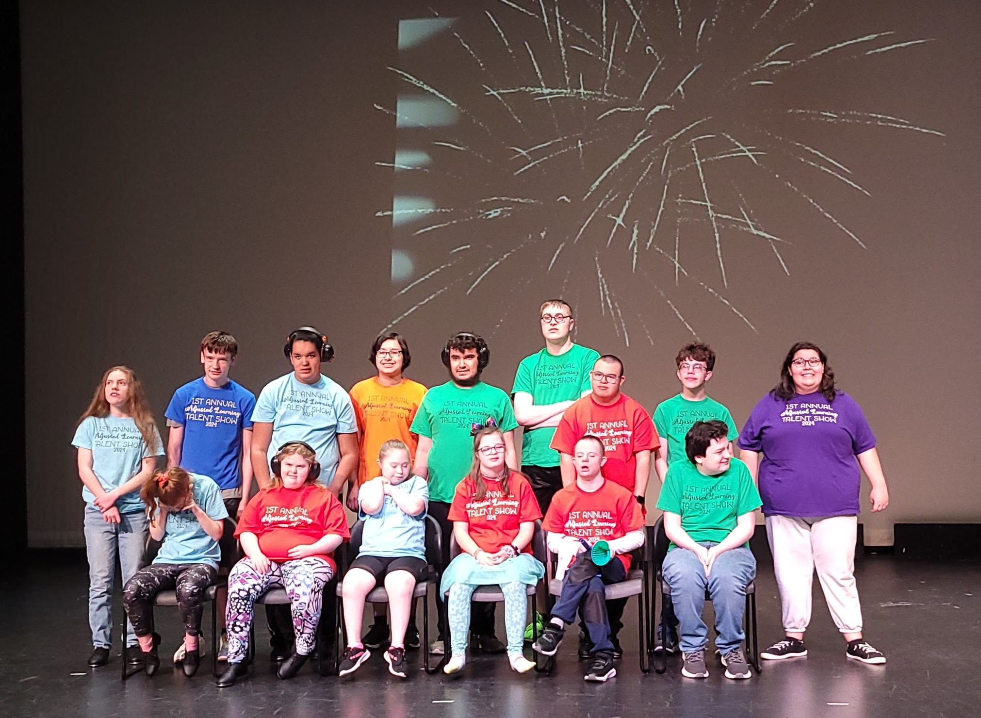 Students on stage wearing talent show t-shirts