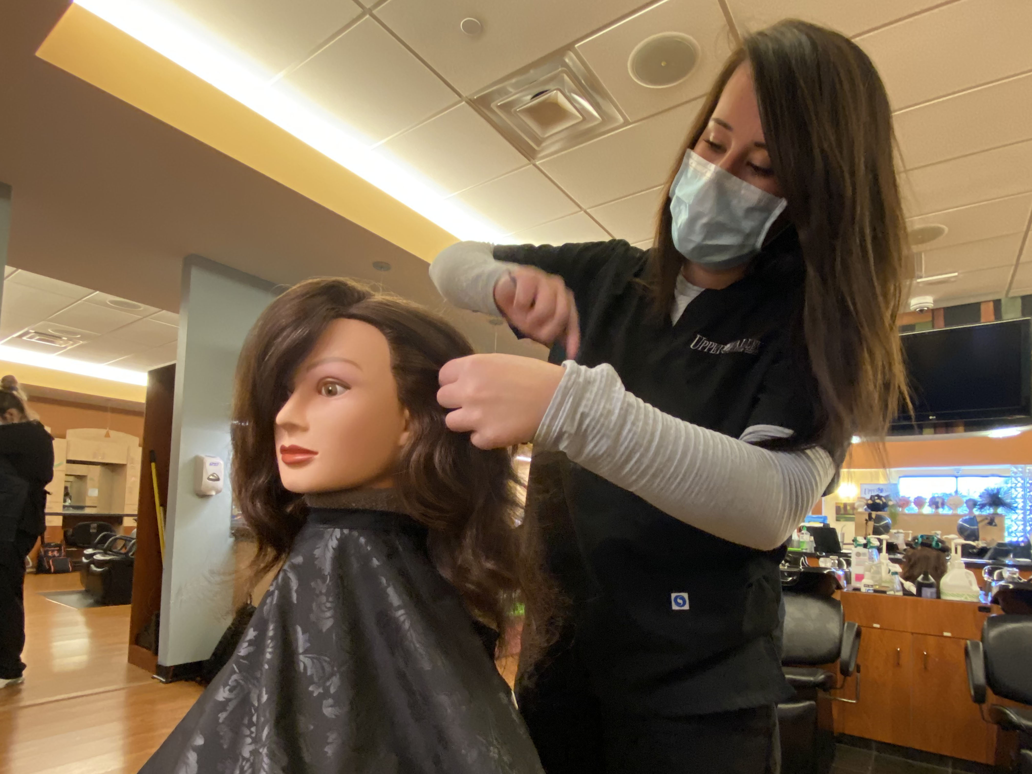 Cosmetology student working on a mannequin's head