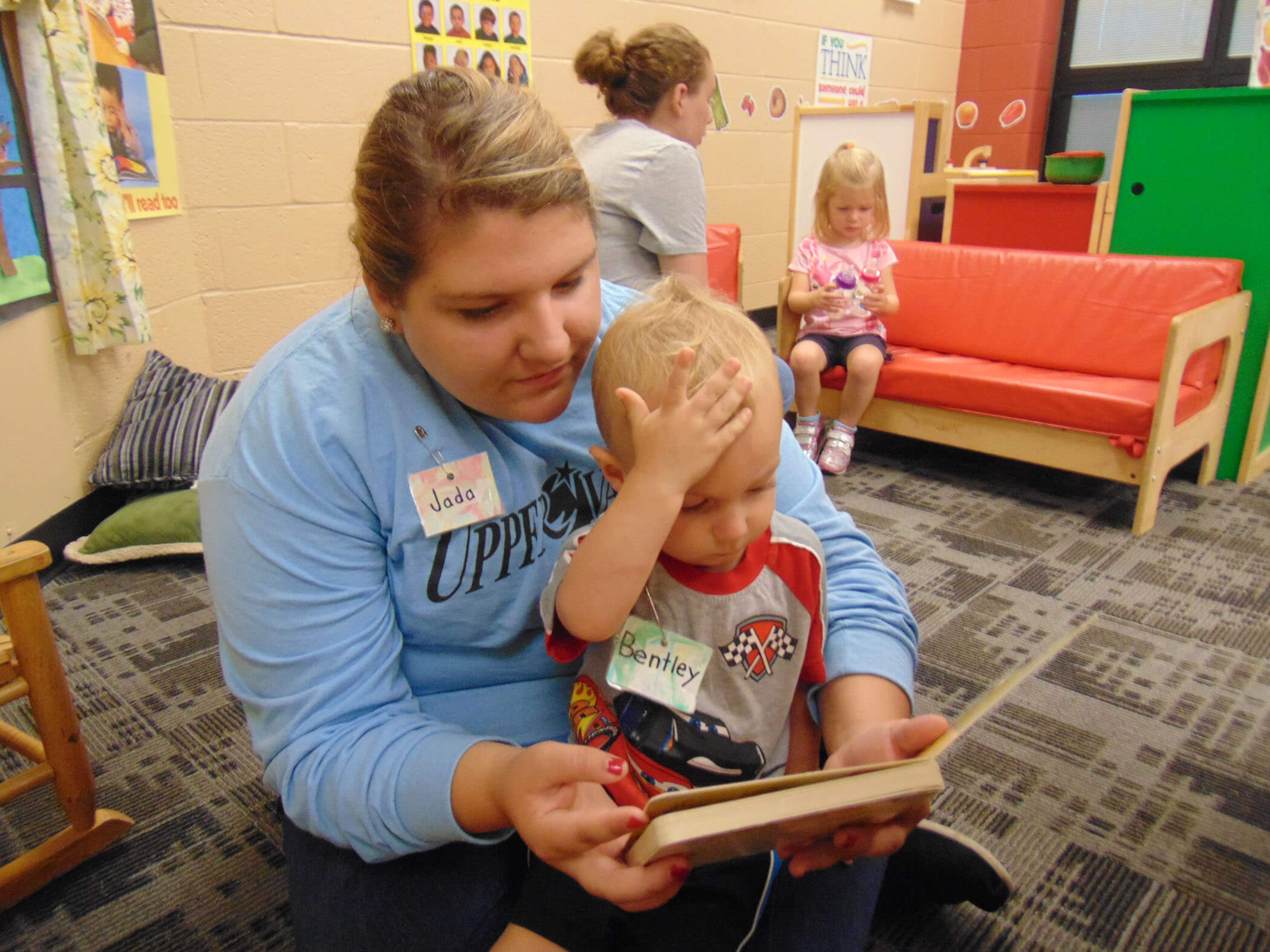 High School student teacher with young preschool student reading a book