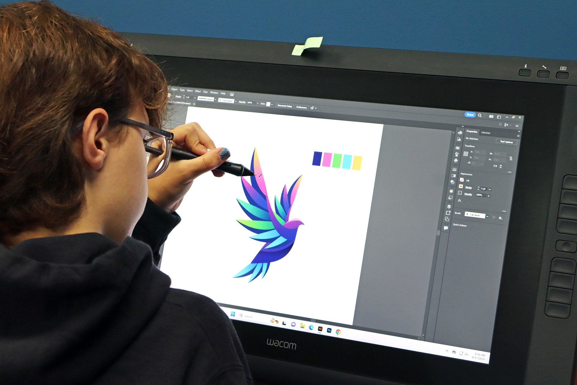 Student draws a colorful bird on a tablet.