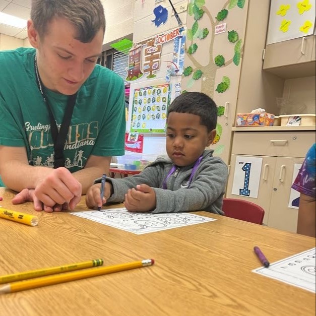 preschool student working with high school student