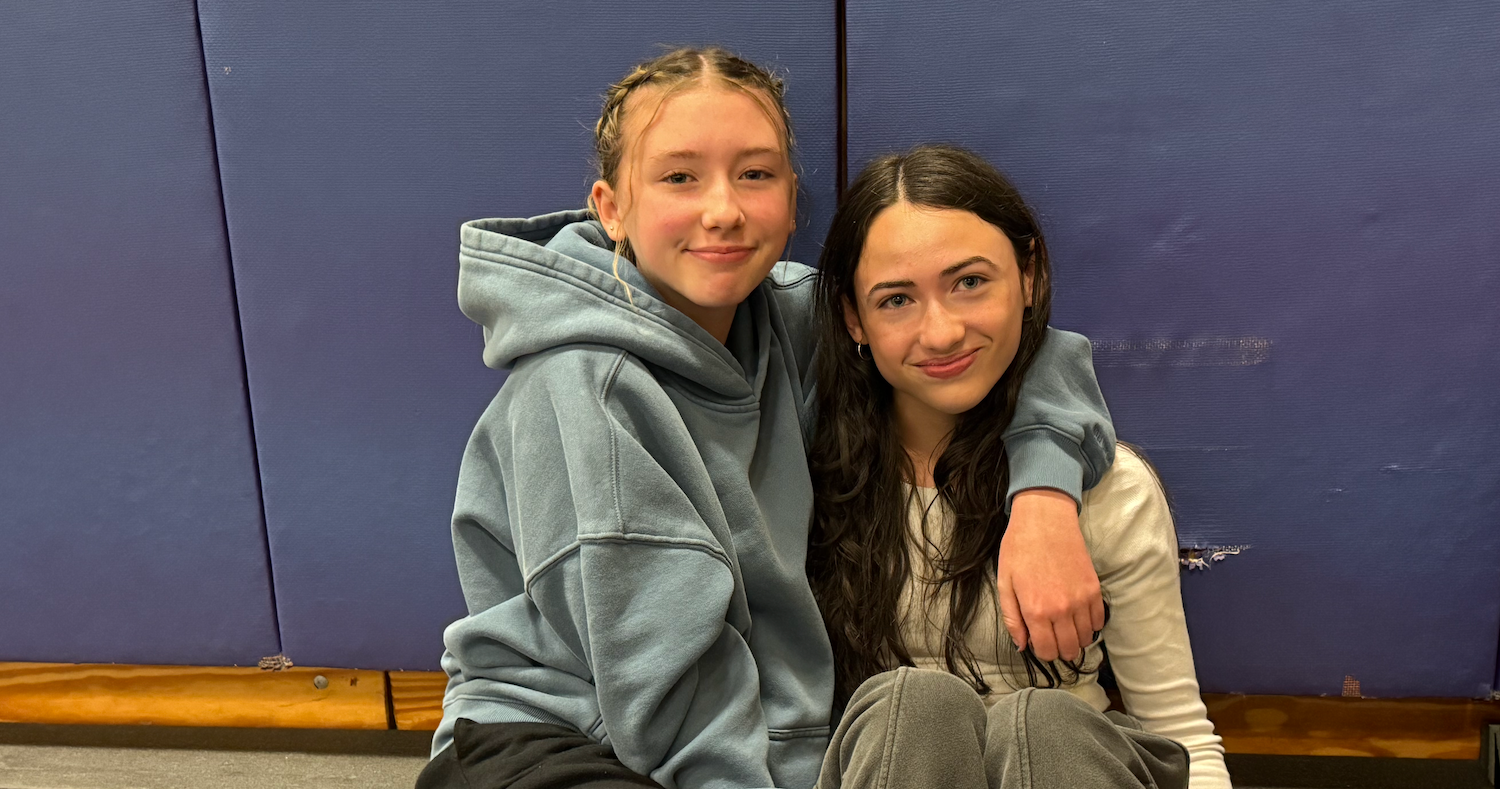 two students wearing grey sweatshirts with blue mat