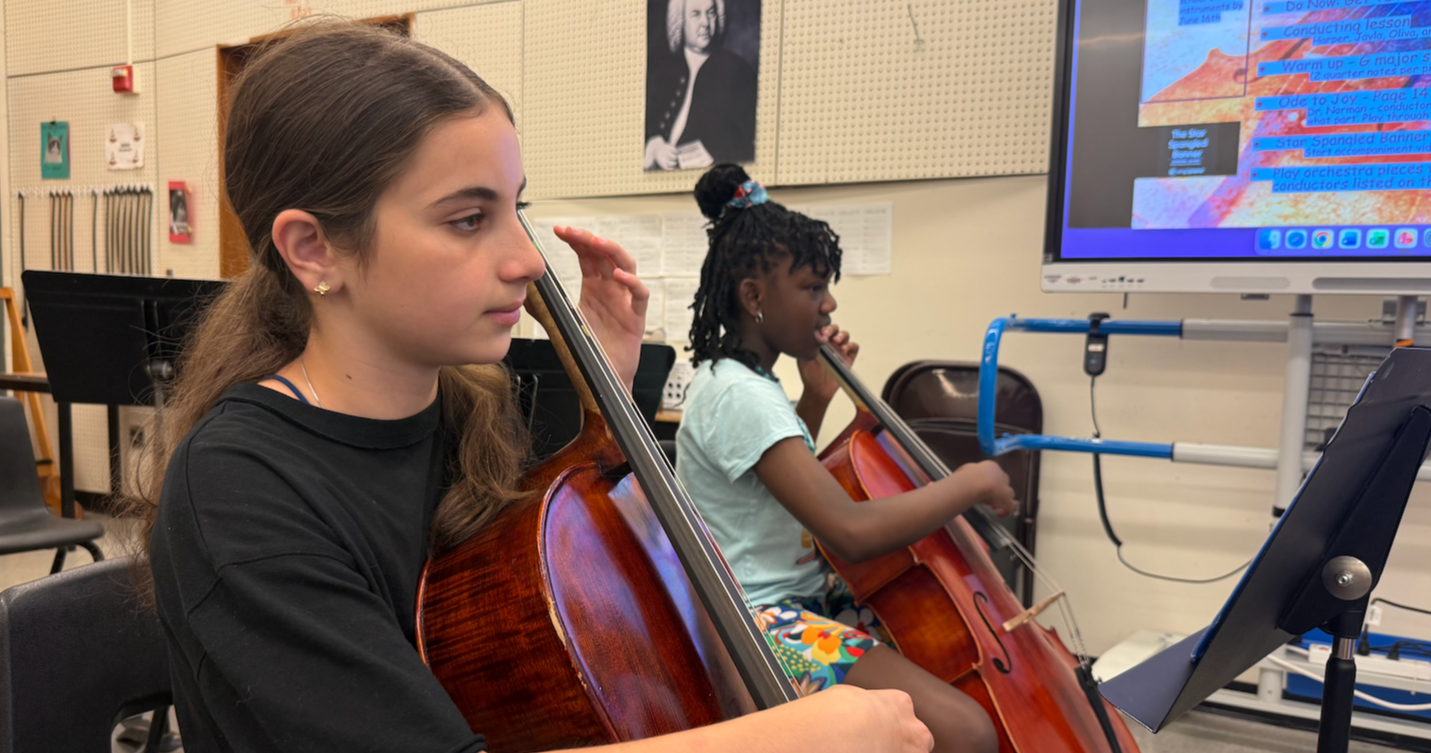 two students holding a cello