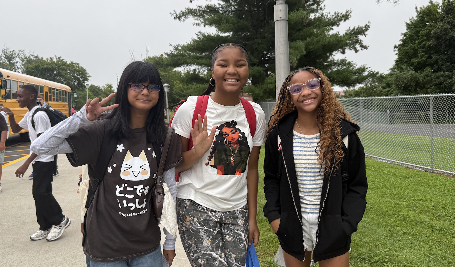 three students standing with backpacks