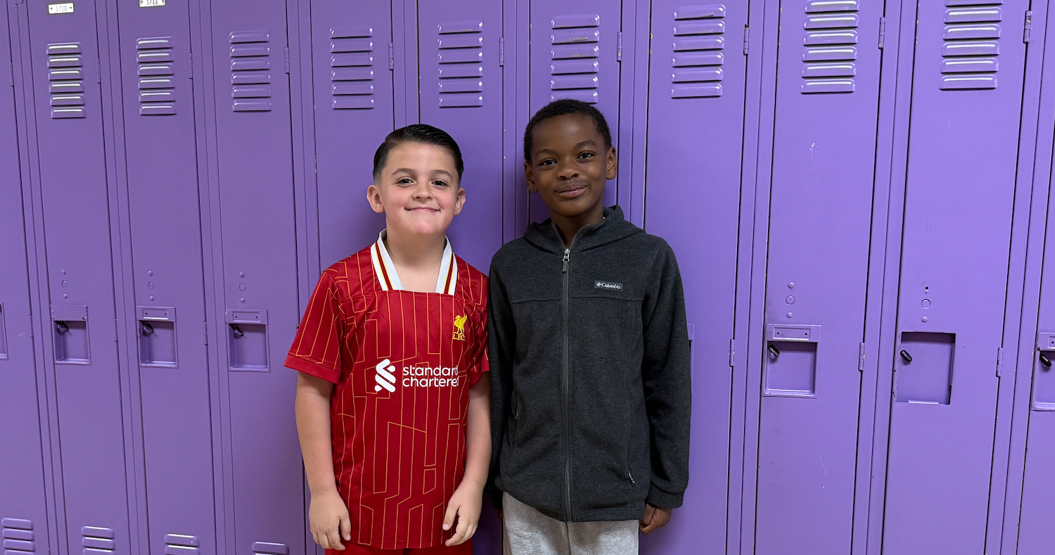 two boys one wearing red and one wearing black standing in front of purple lockers