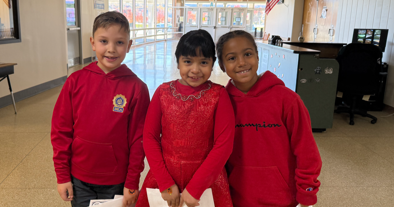 three students wearing red shirts and dresses 