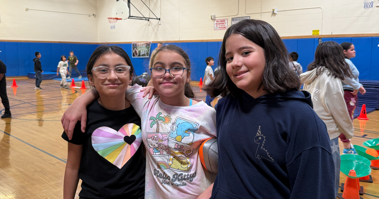 three students standing in gym
