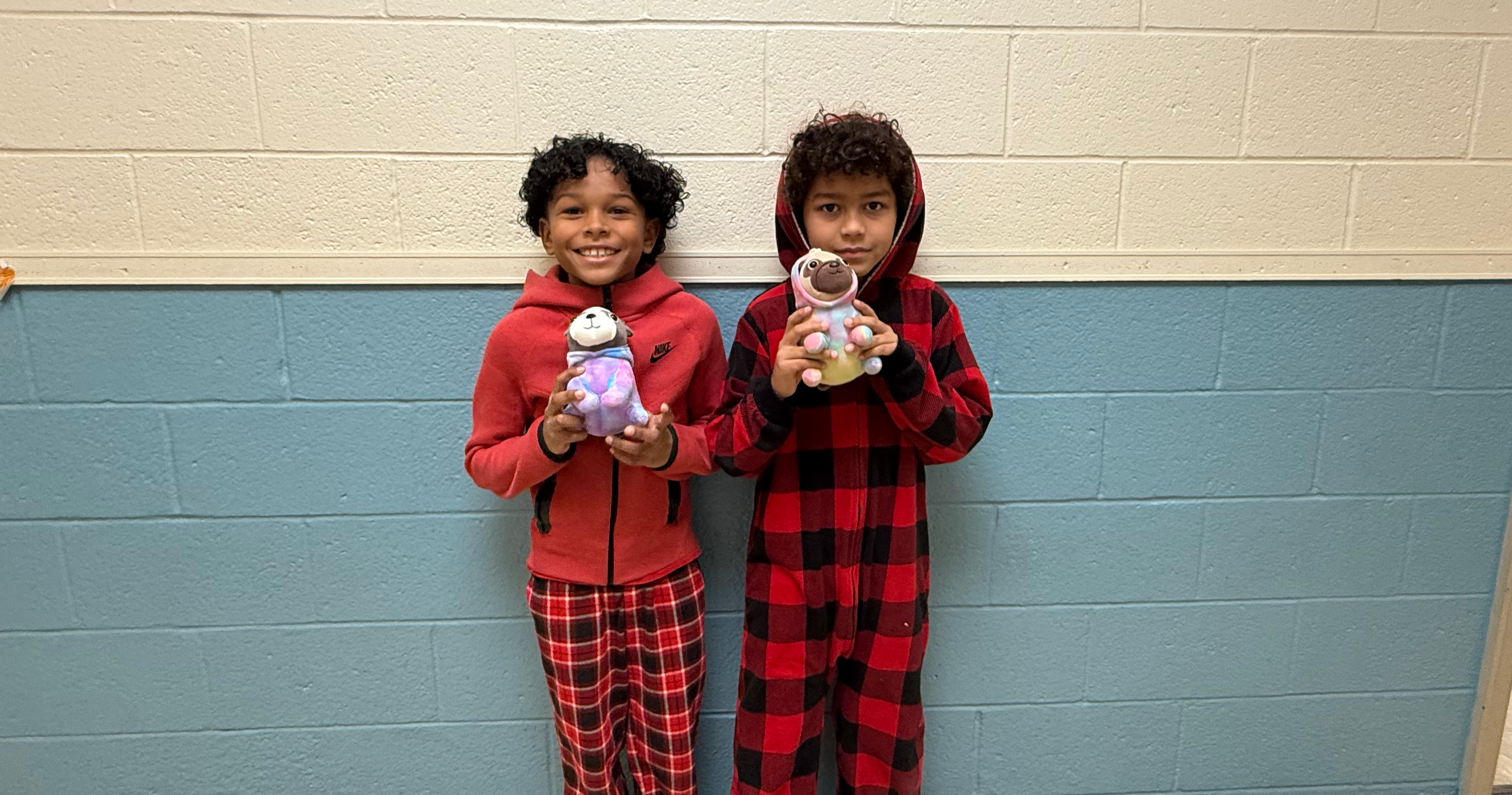 two students wearing red holding stuffed animals