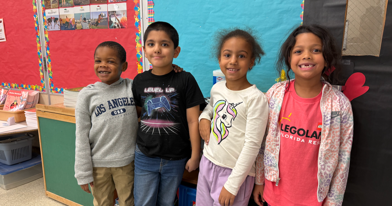 four students standing in a line wearing various color shirts