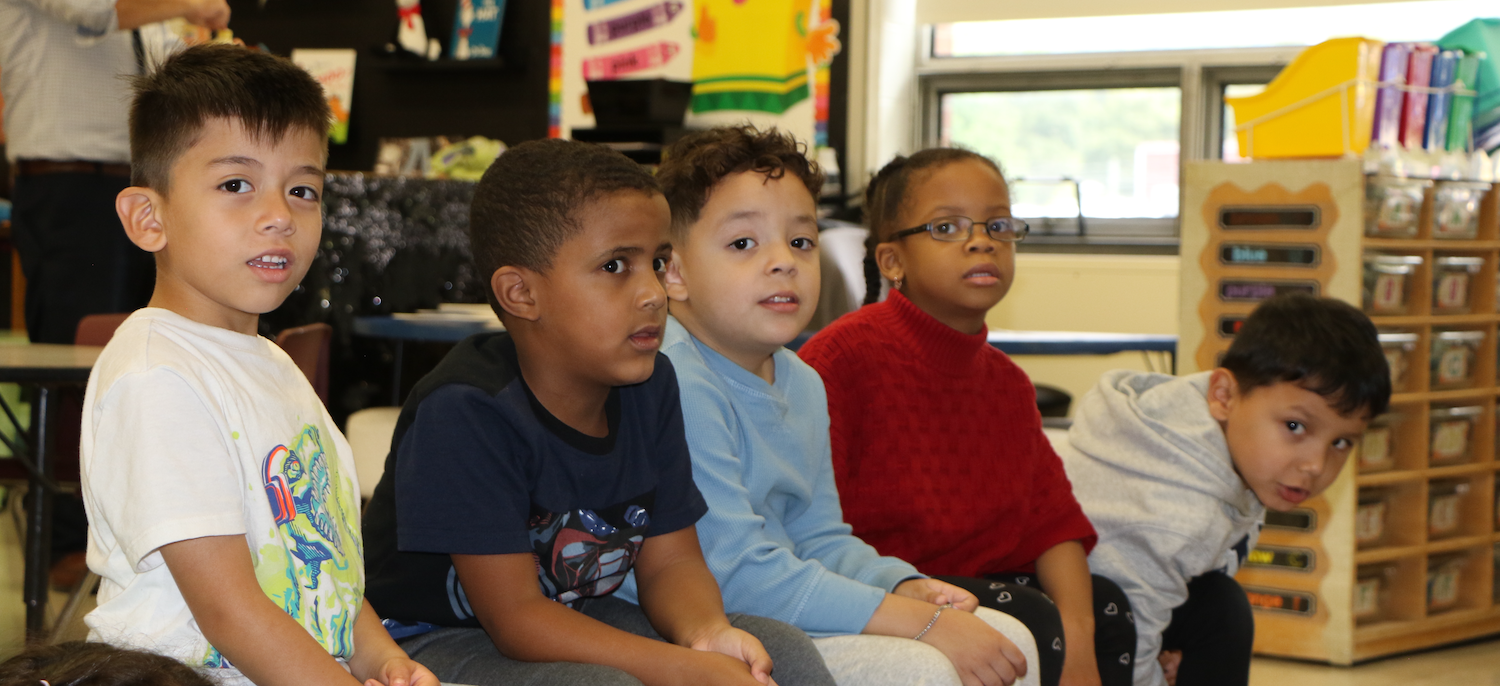 students wearing black, blue and red shirts sitting in class