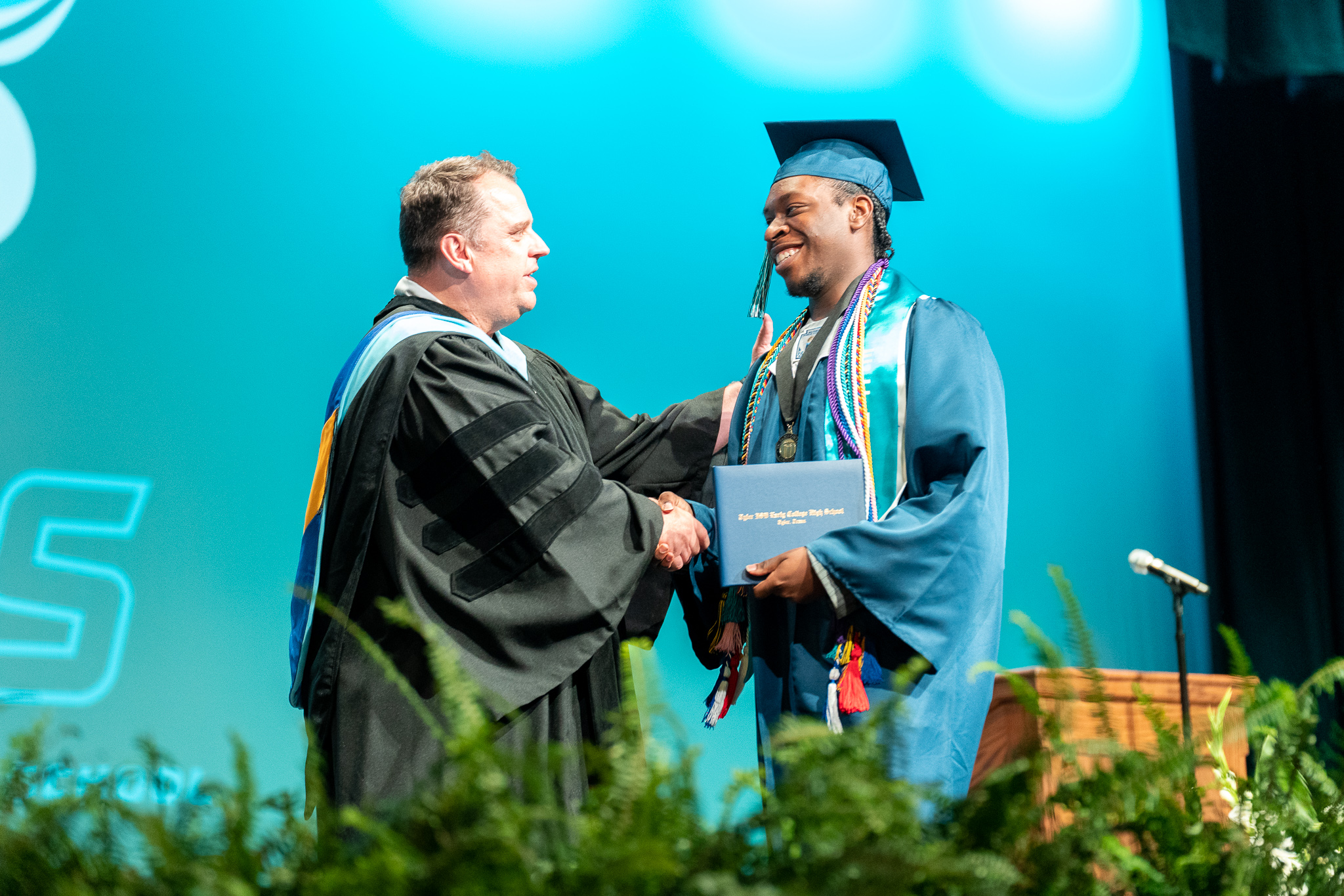 Student and superintendent shaking hands at Early College High School Graduation.