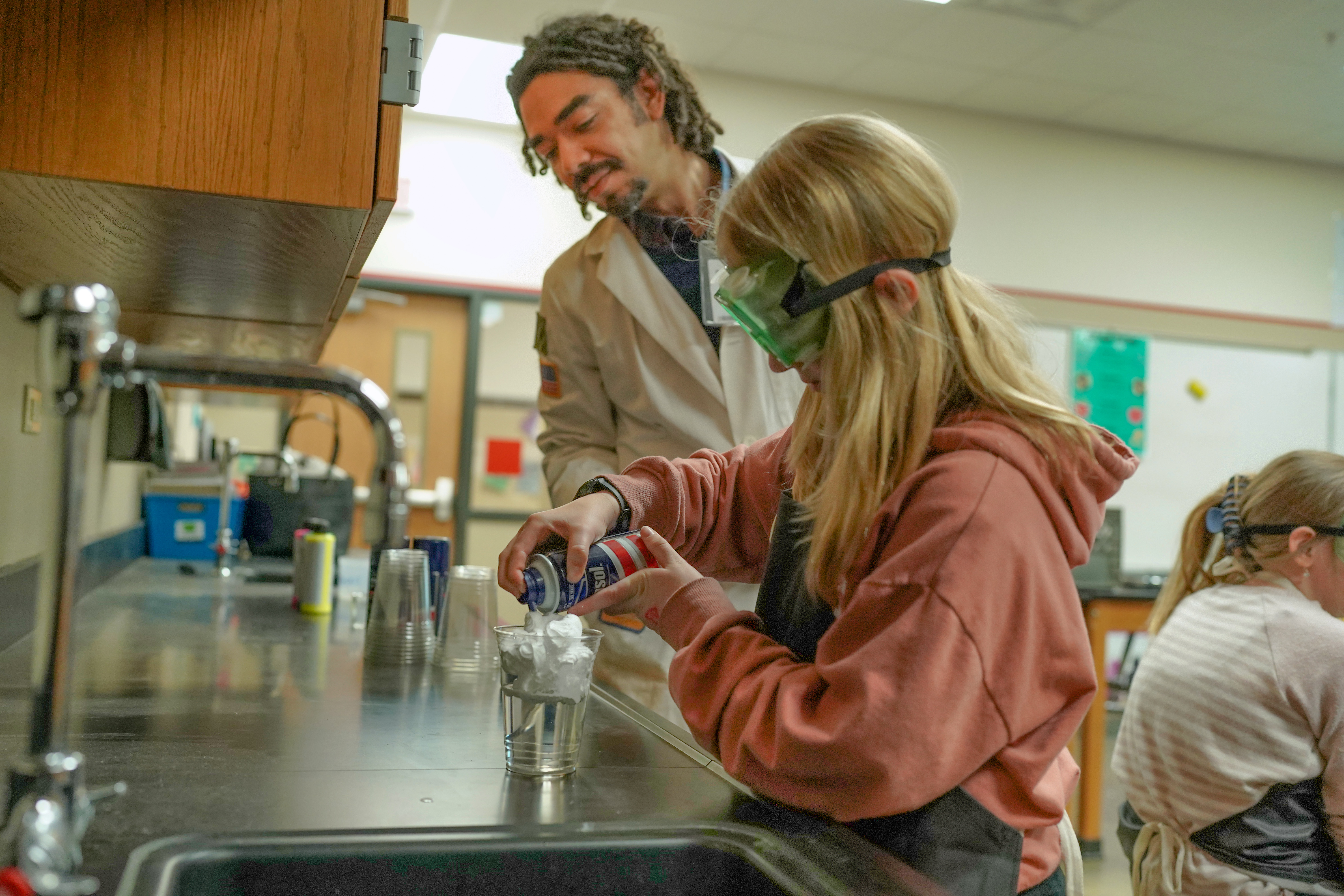 Teacher helping a student conduct a science experiment