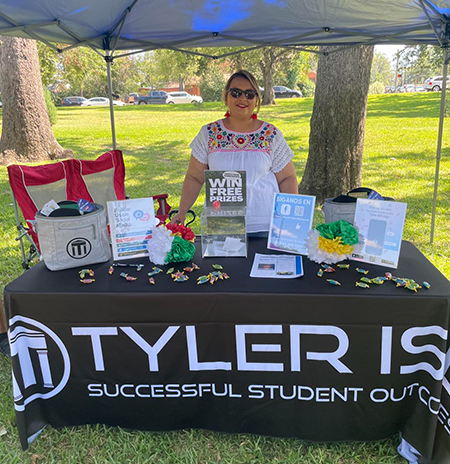 woman stands behind table with information about Tyler ISD
