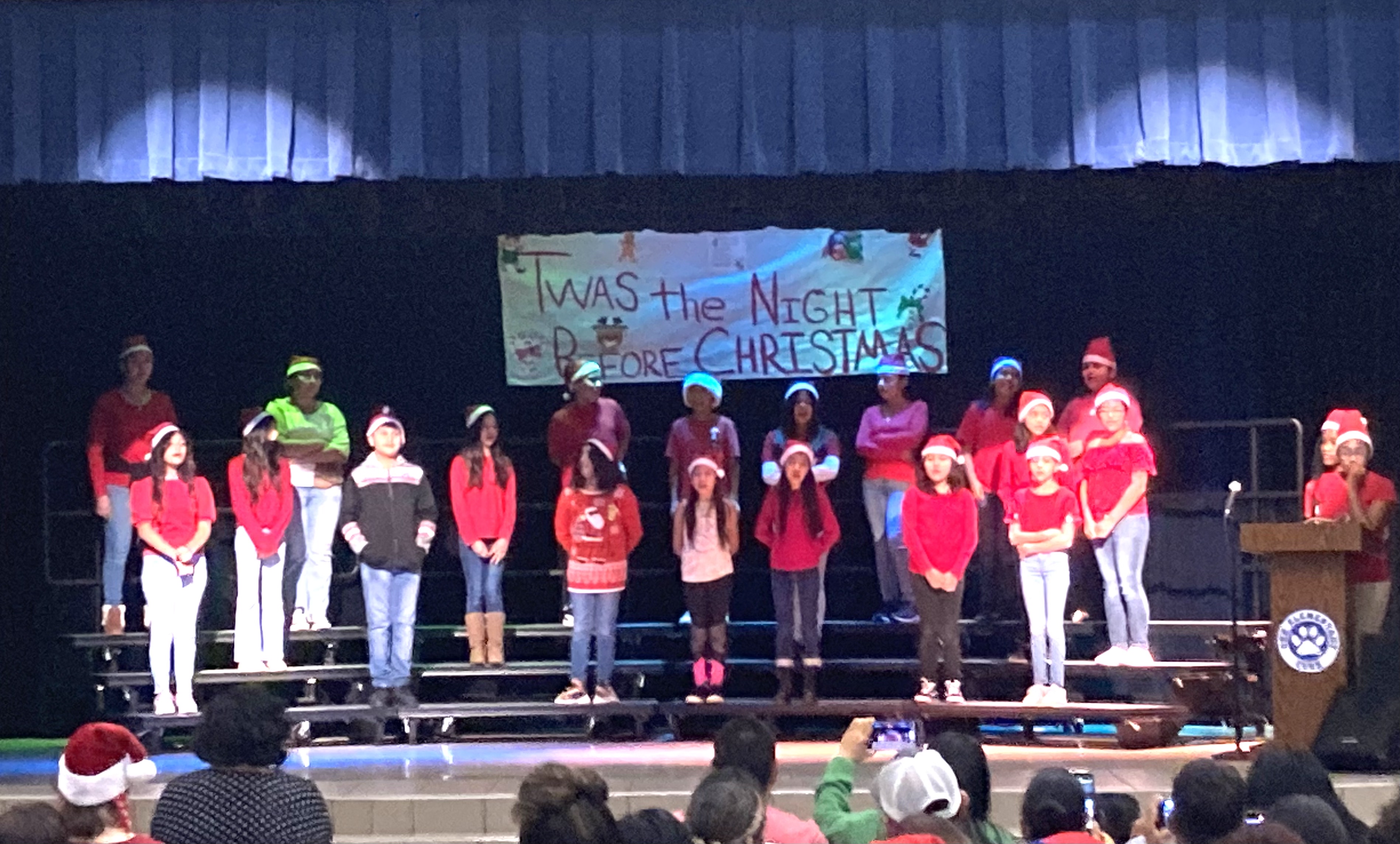 elementary aged students stand on stage singing