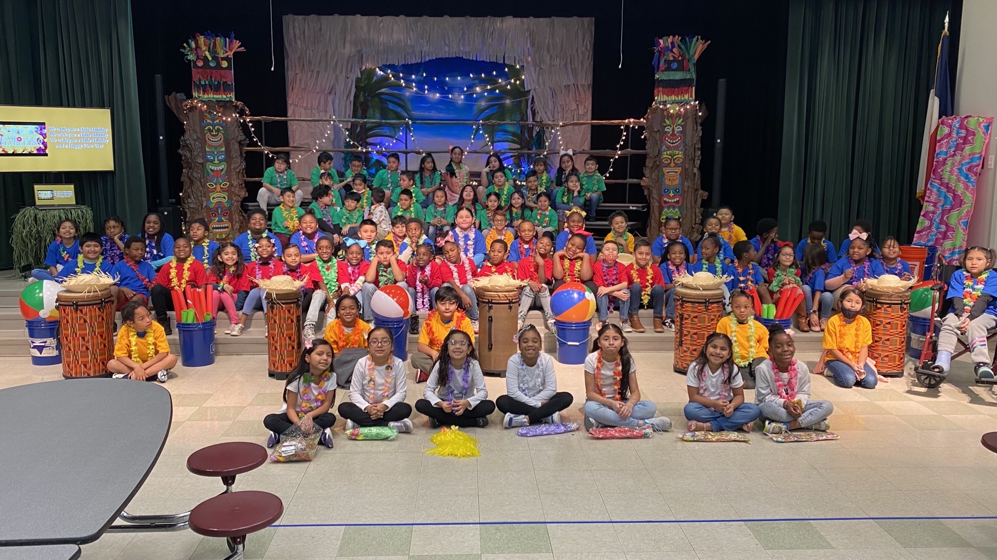 elementary age students dressed in Hawaiian attire in front of a stage