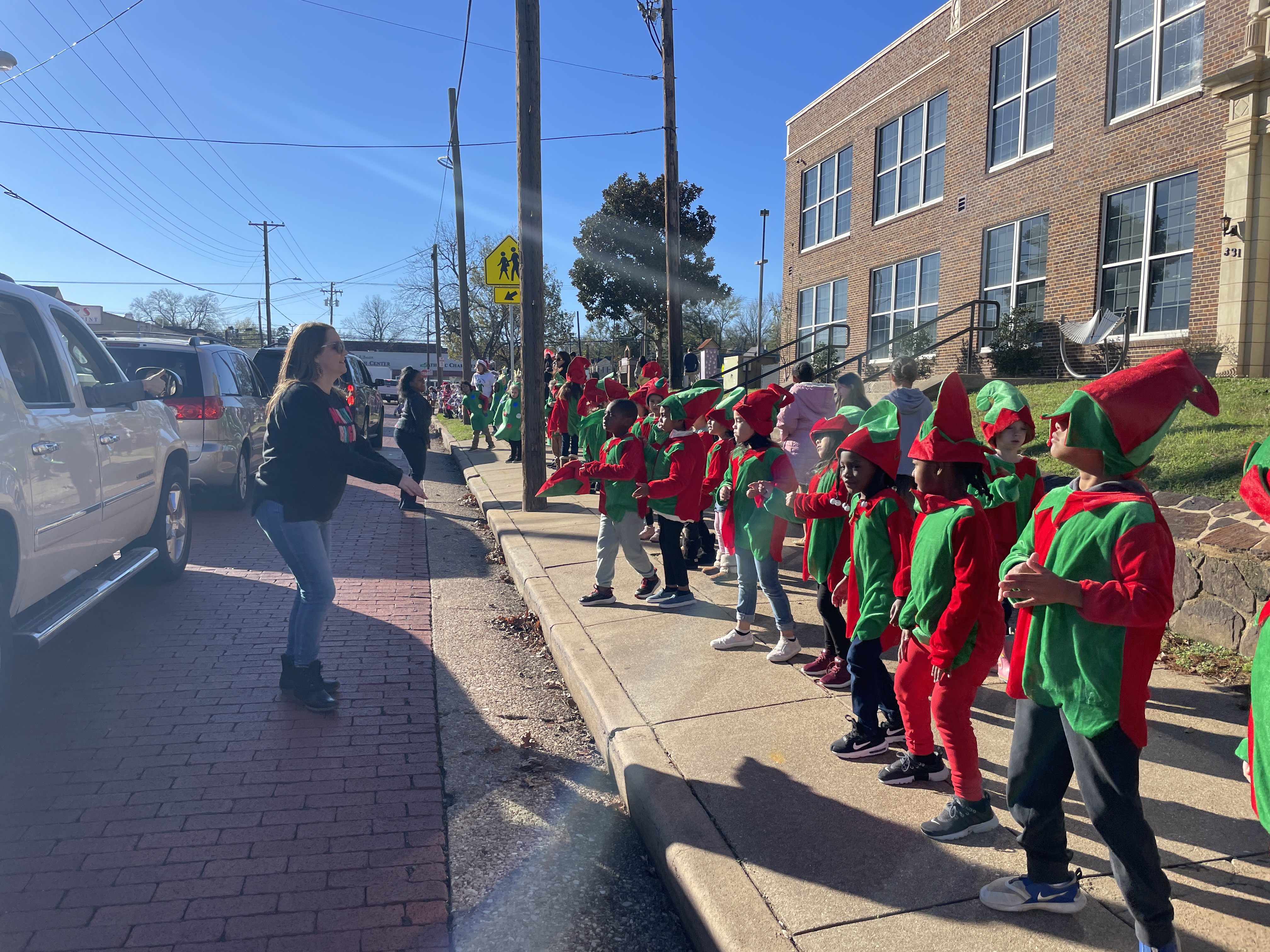 children standing along the sidewalk dressed as elves