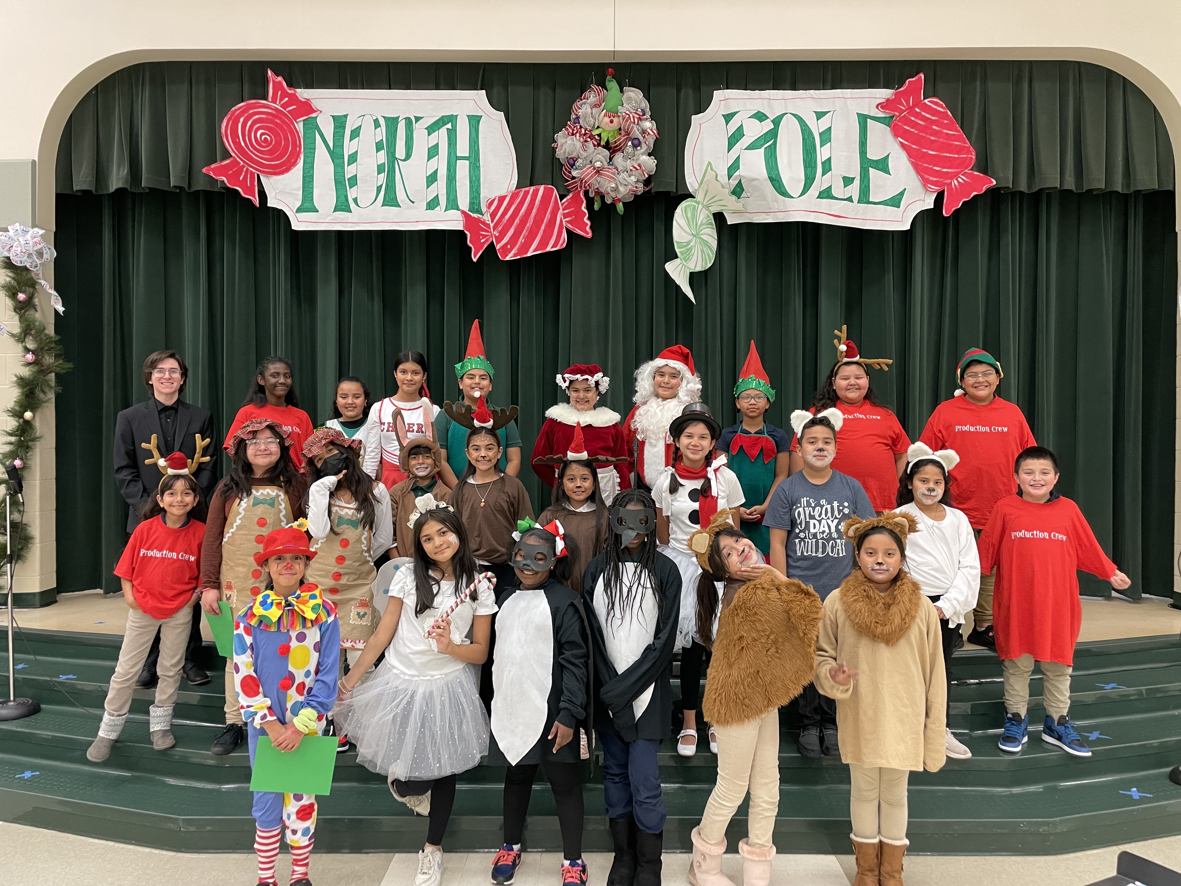 group of students on stage dressed as Christmas characters - Santa, gingerbread men, elves