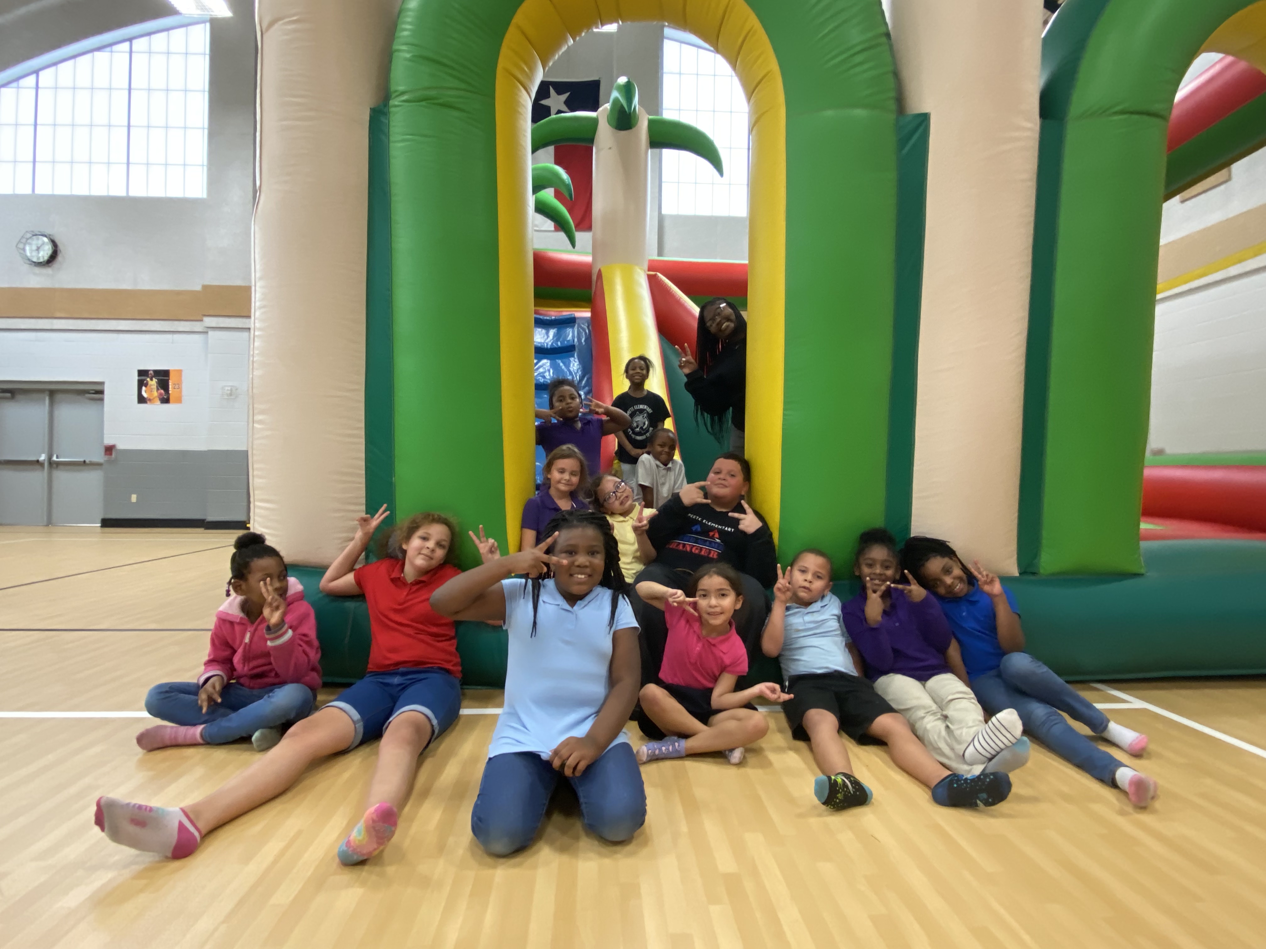 elementary aged students sitting in front of a giant bounce house