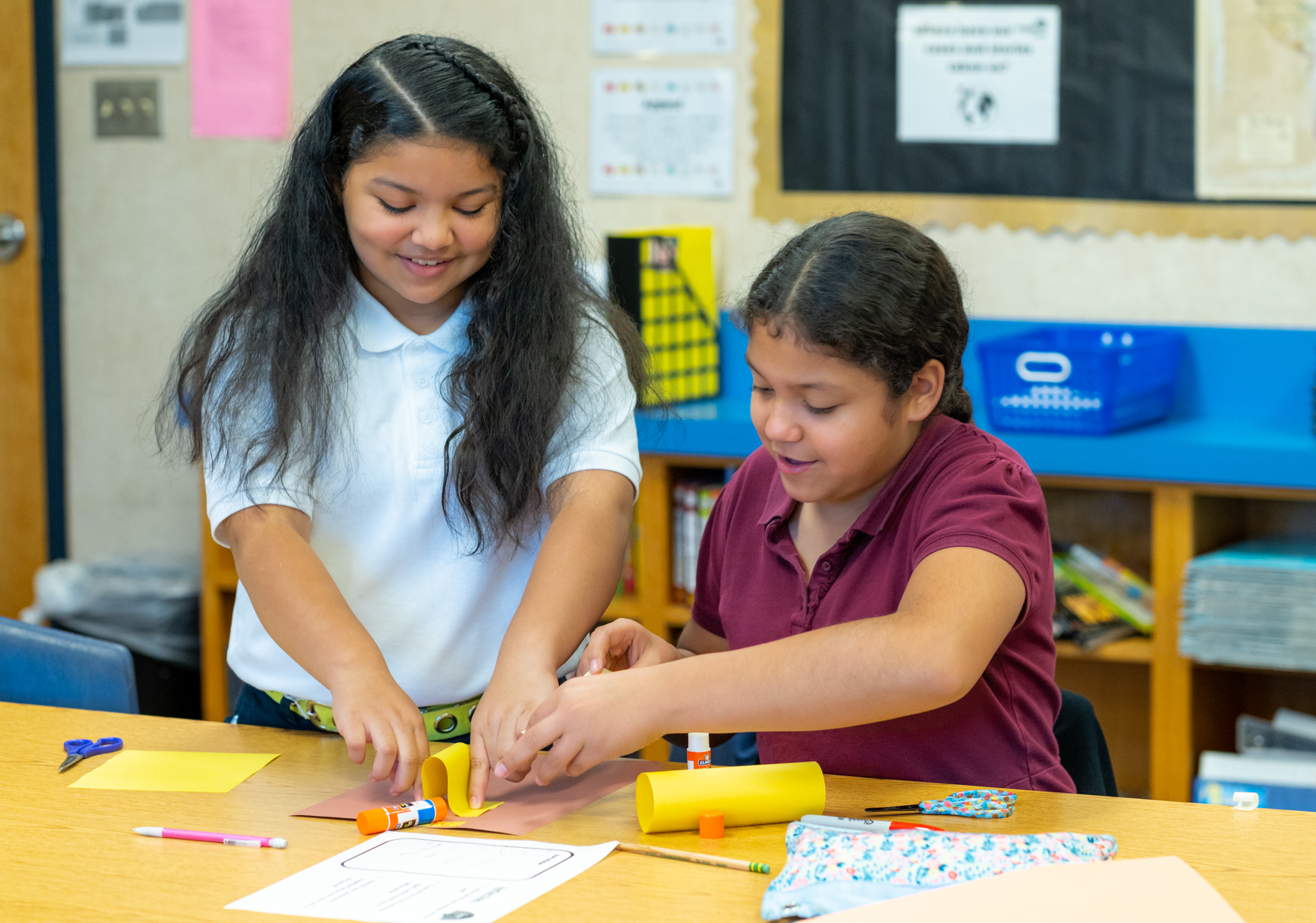 two female students working on a construction paper project together