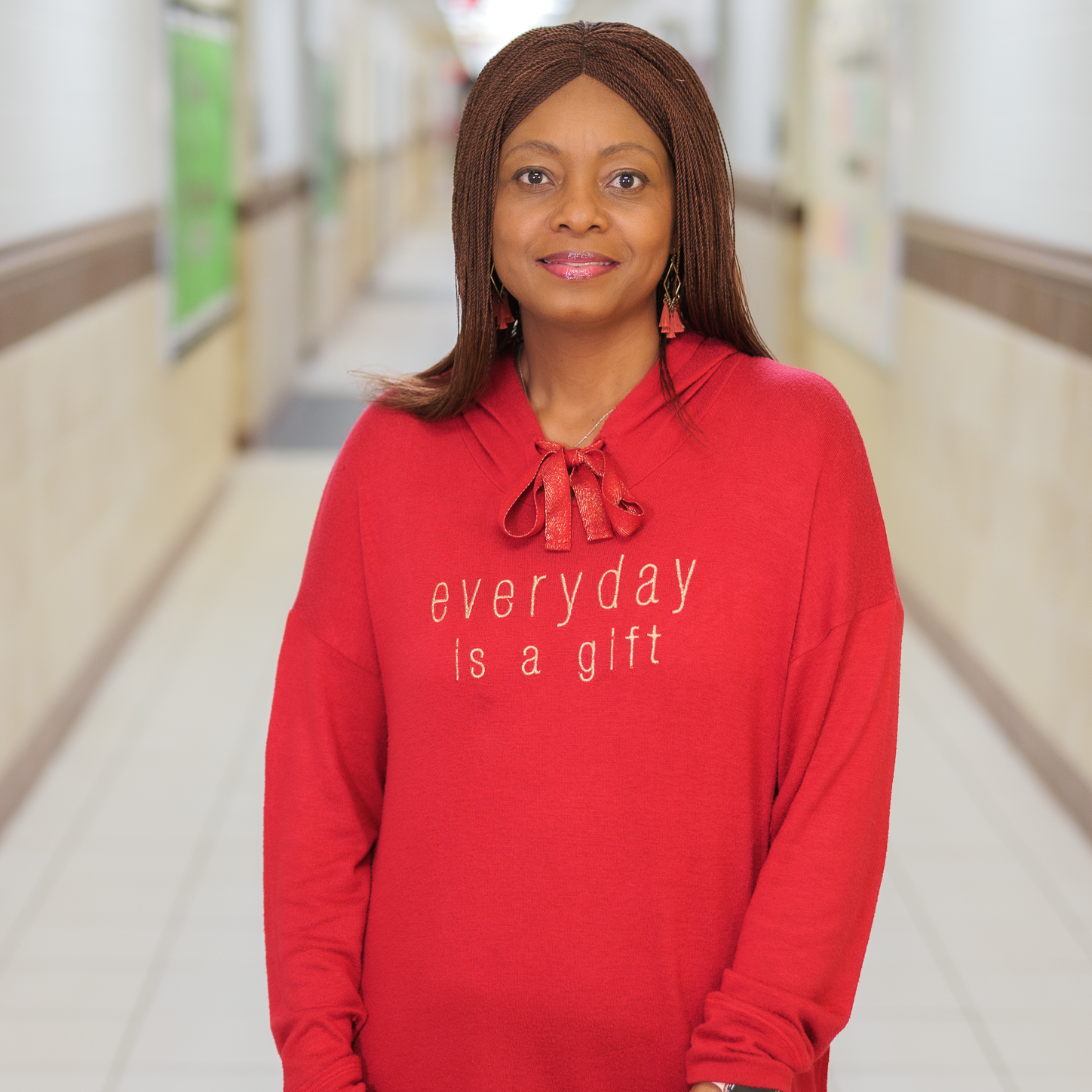 African American woman wearing a red sweatshirt standing in a hallway