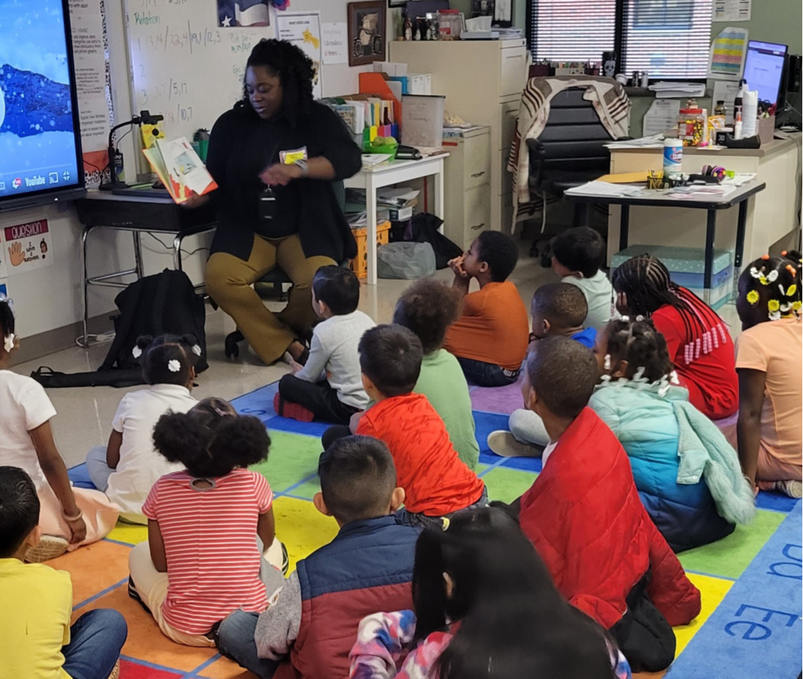 woman reading a book to children sitting on the floor