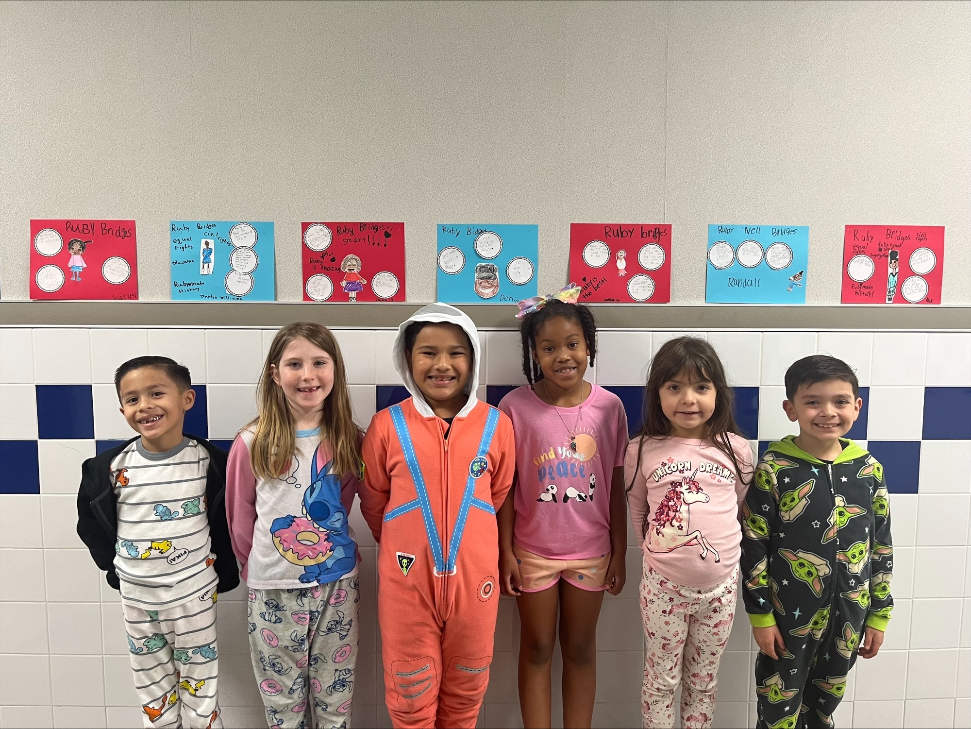 elementary age kids leaning against a wall wearing pajamas