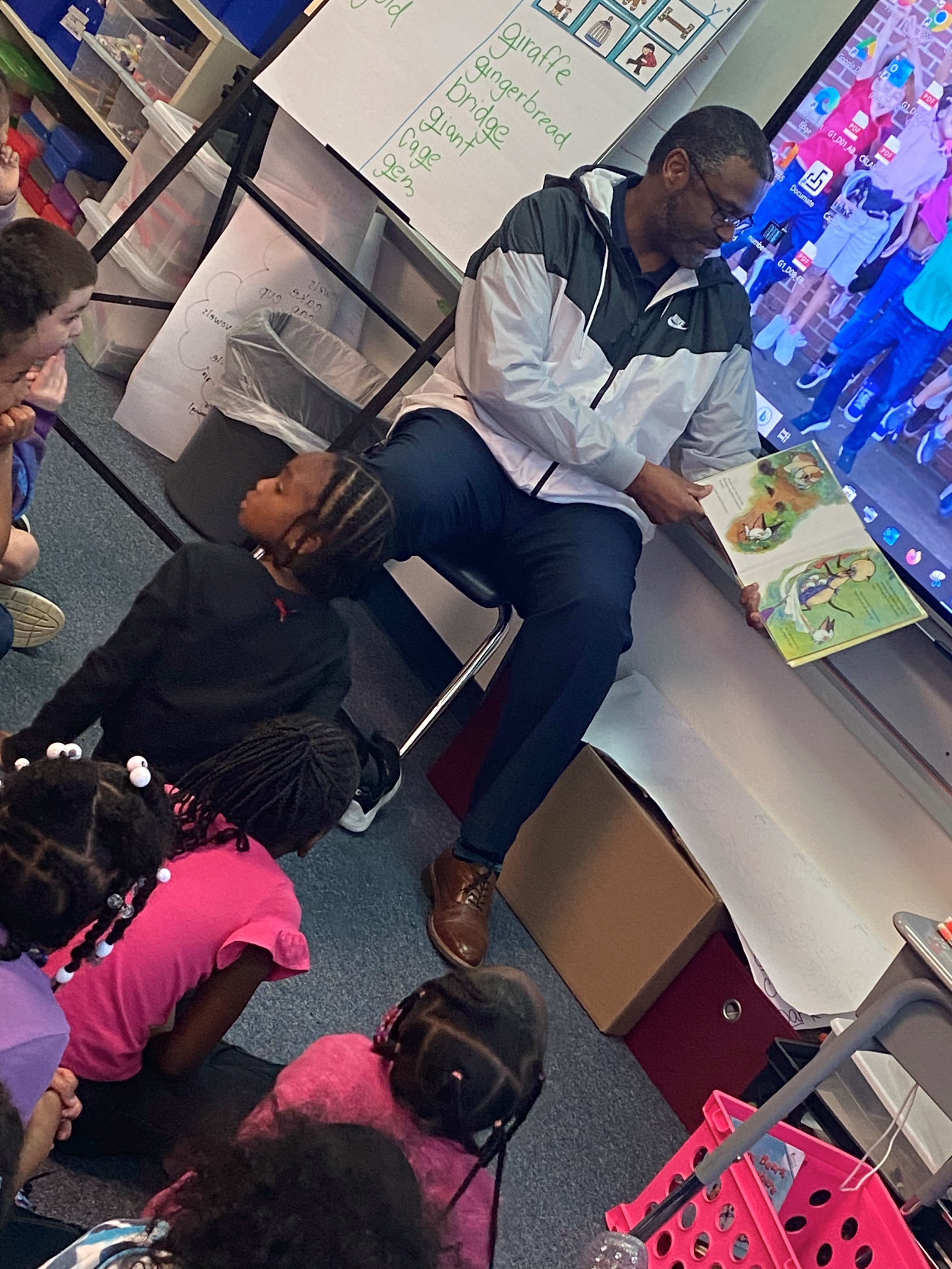 man reads a book to a classroom of kids