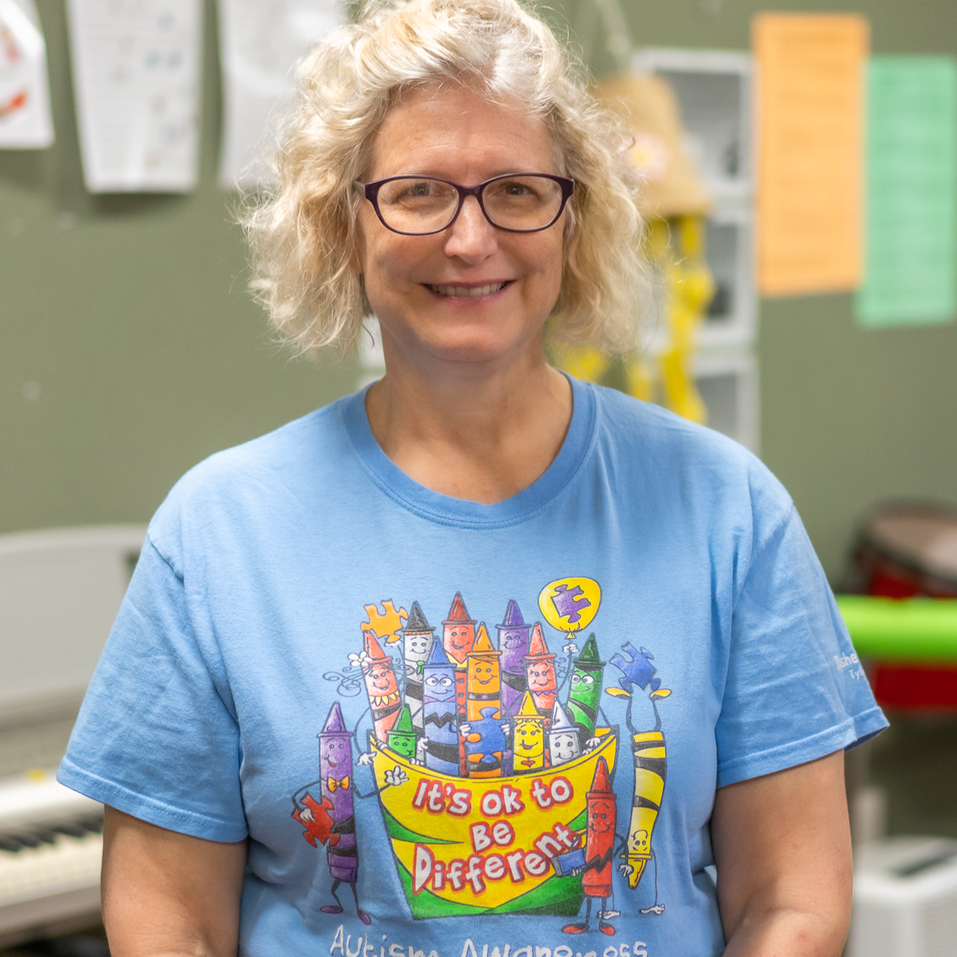Caucasian woman with short blond hair wearing a blue t-shirt