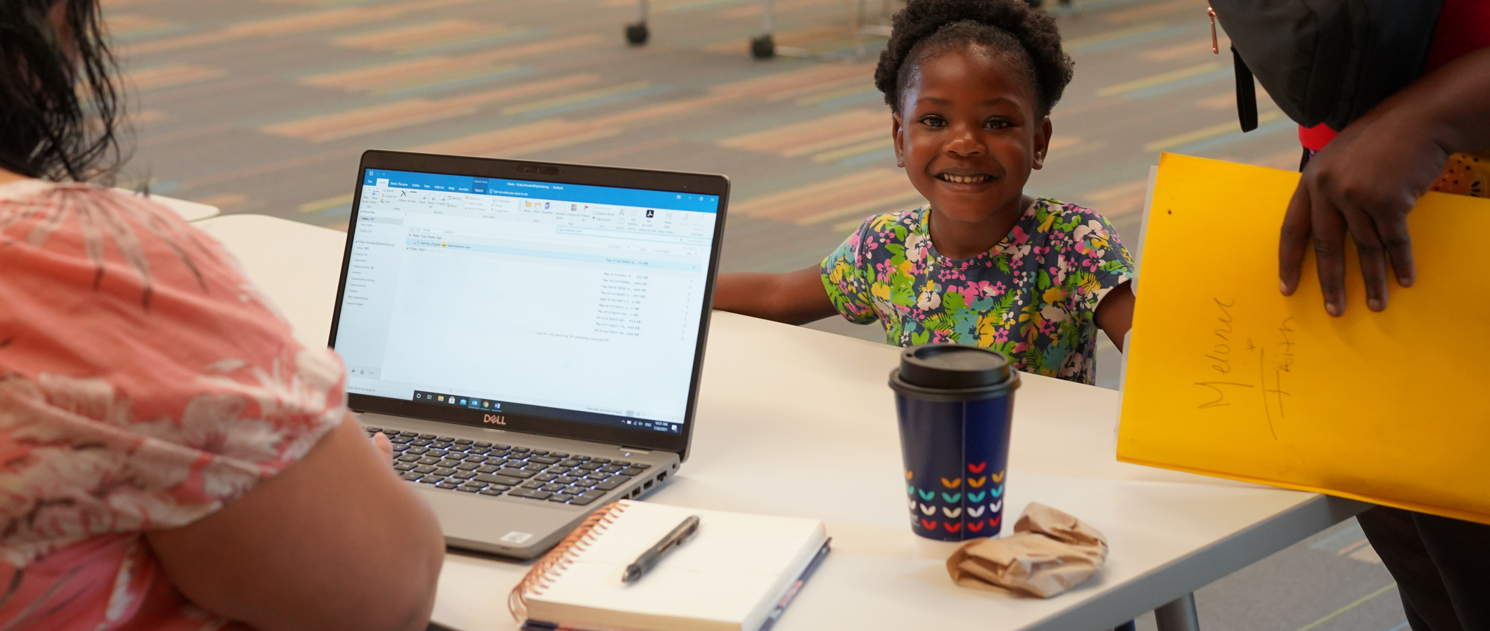 computer screen on desk with small child on other side smiling