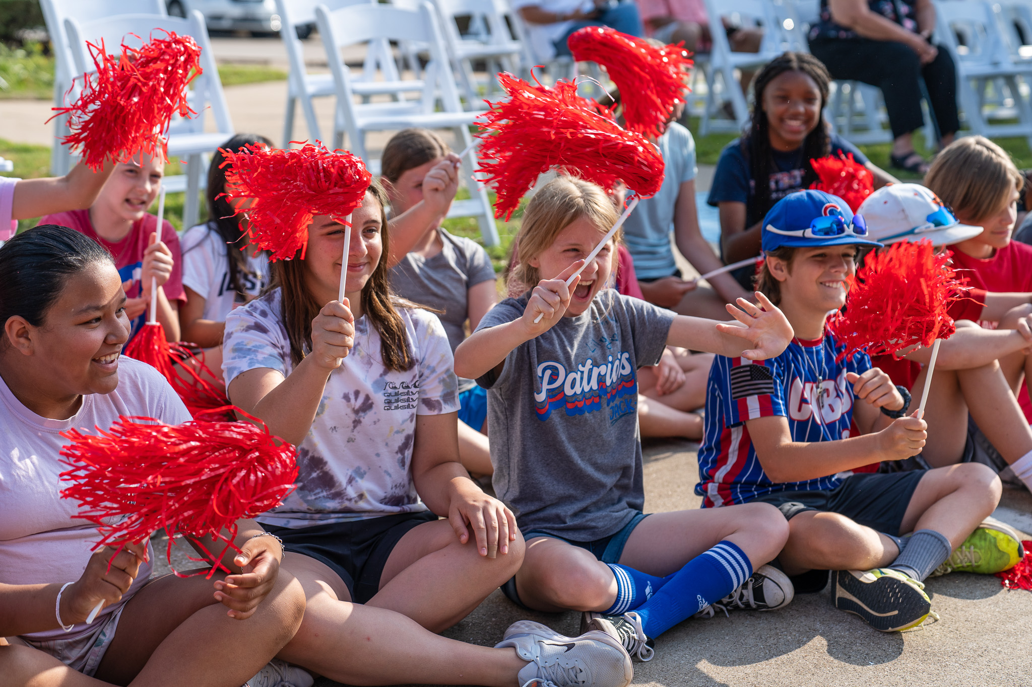 group of elementary age students sitting together waving pom poms