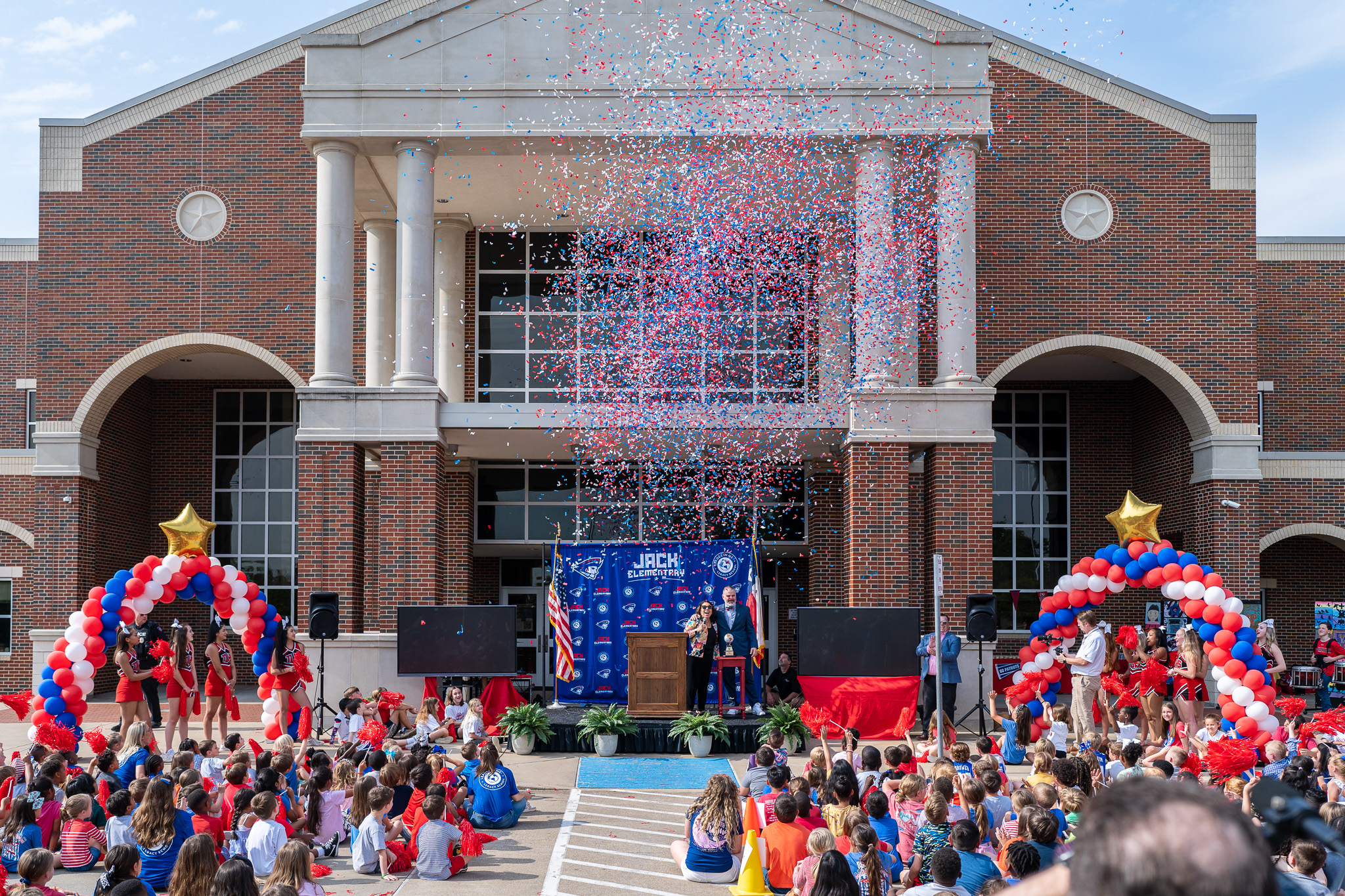 confetti flying through the air in front of elementary school with students standing out front