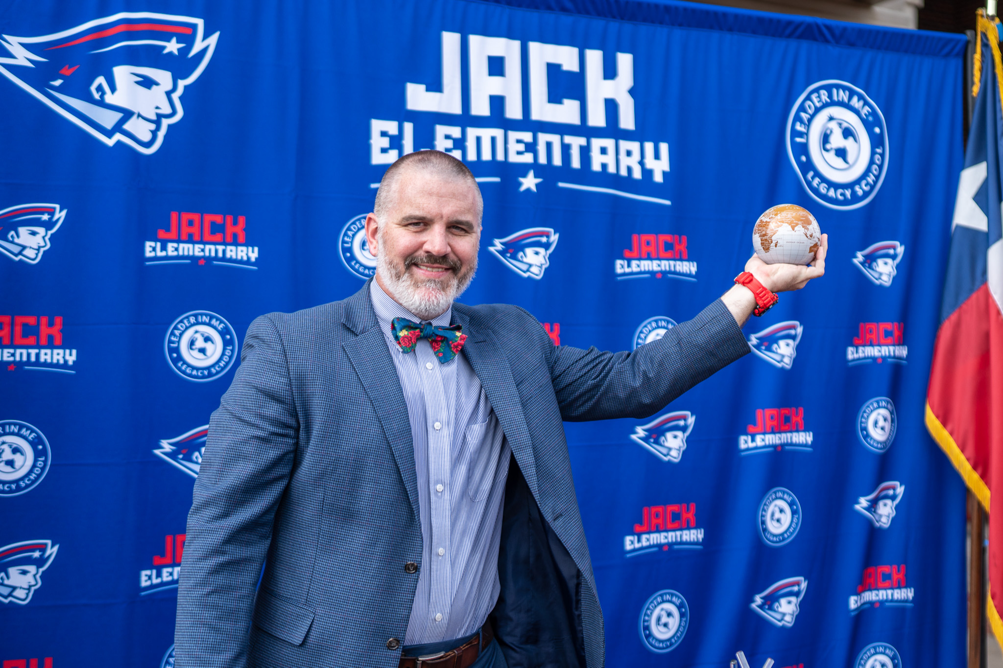 man stands in from of Jack Elementary sign with his arms spread wide