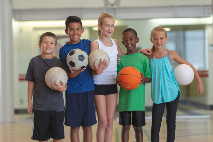elementary age kids holding sports balls