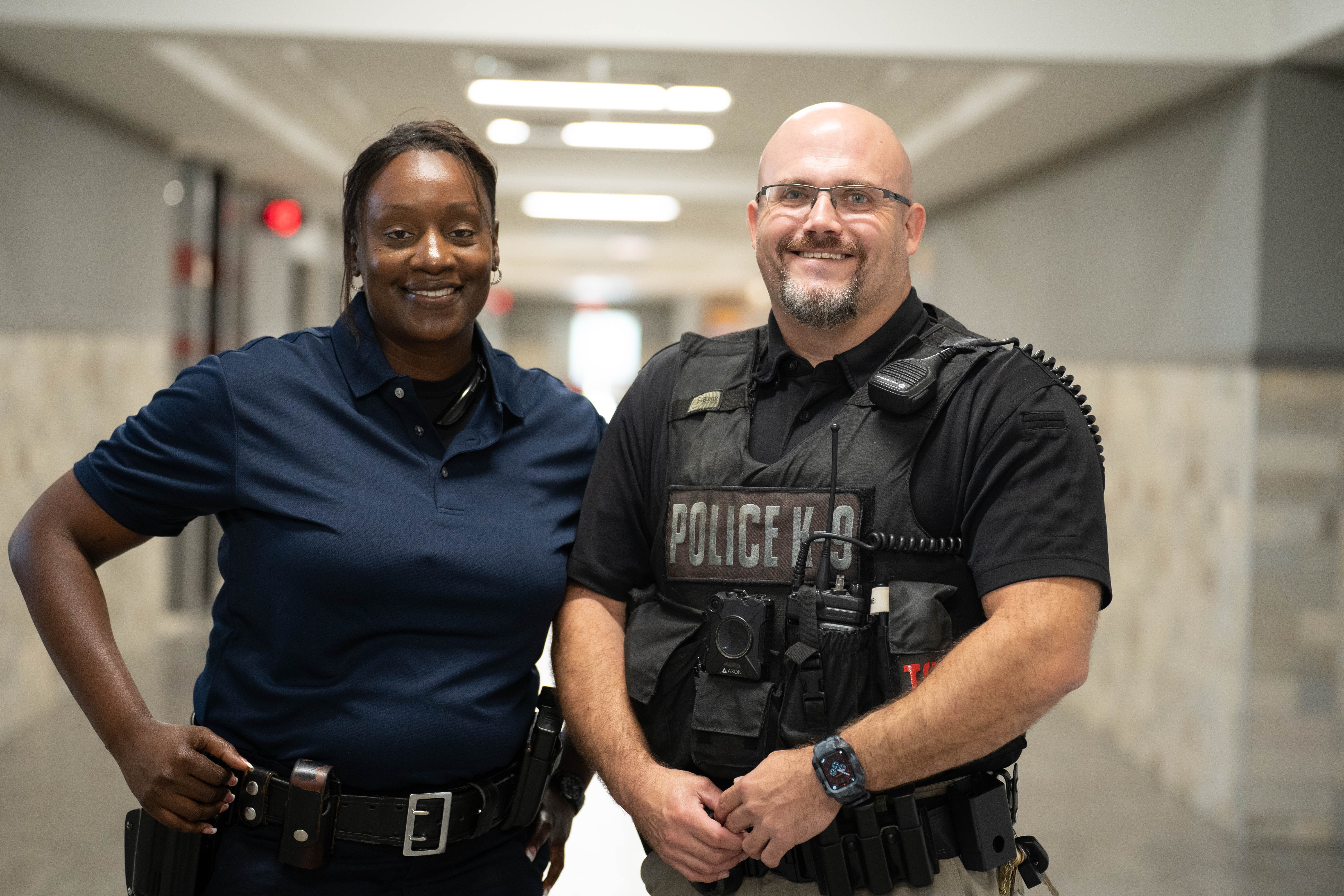 man and woman police officers in uniform standing in school hallway