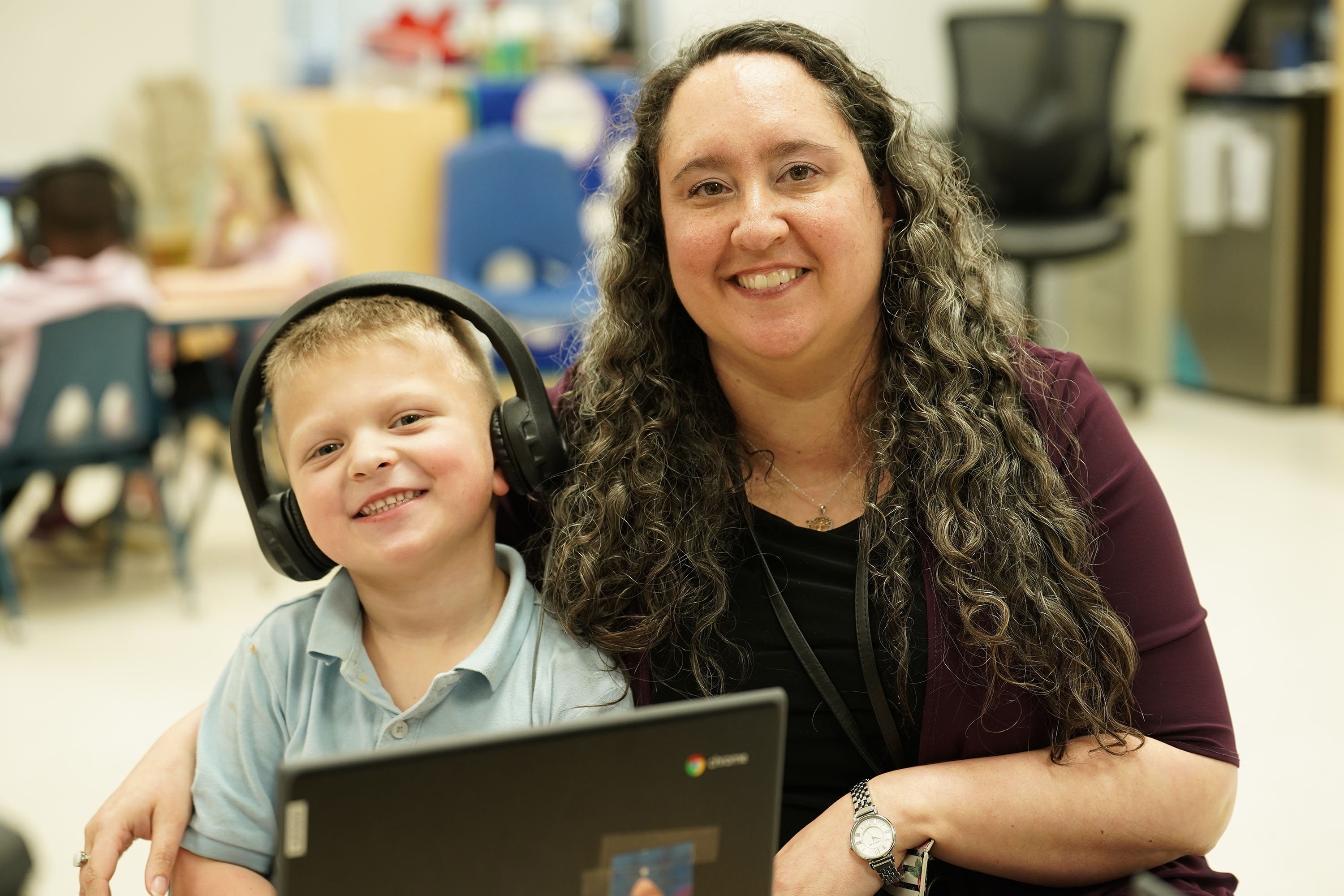 young boy wearing headphones sitting next to female with long curly hair