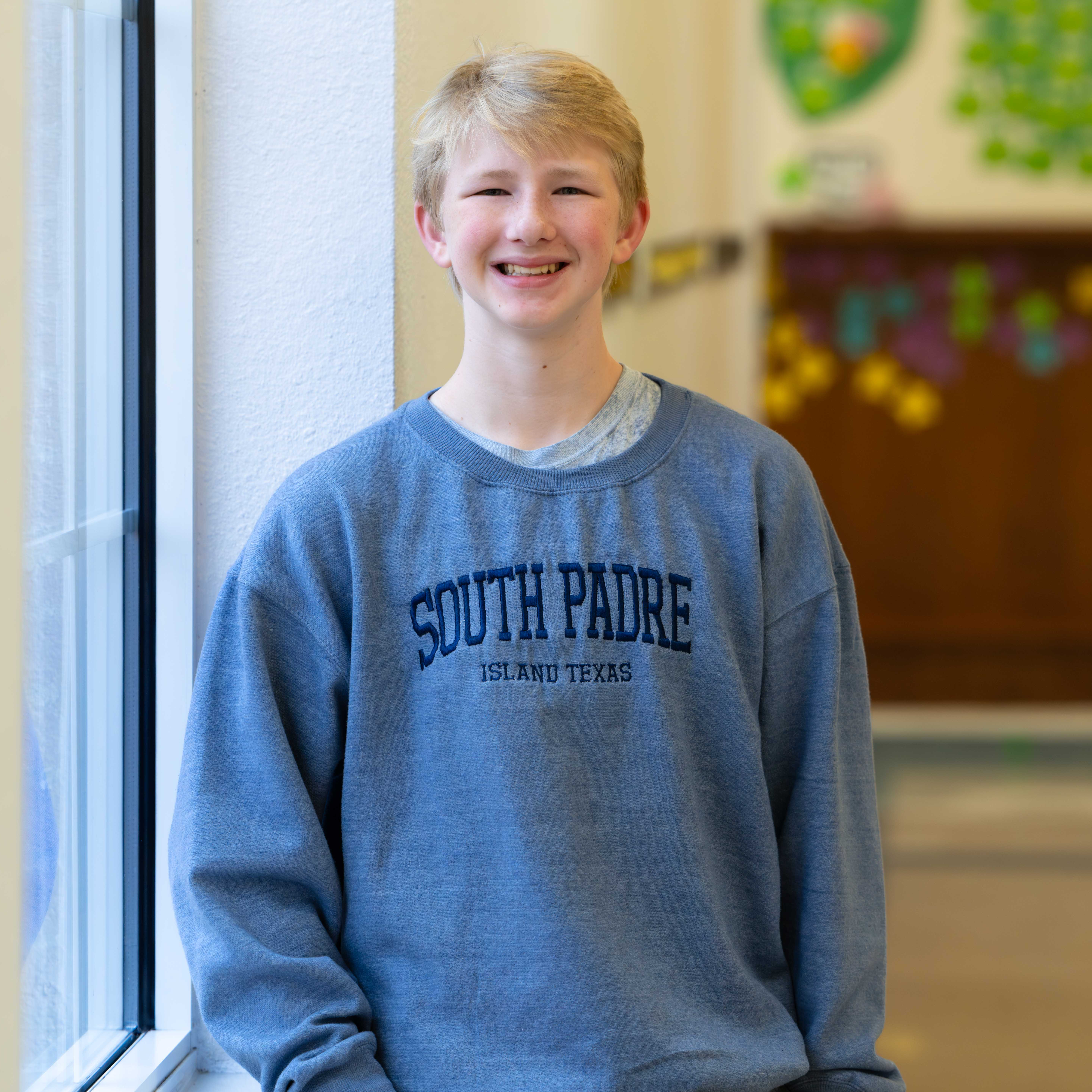 Caucasian teen boy wearing a blue South Padre sweatshirt