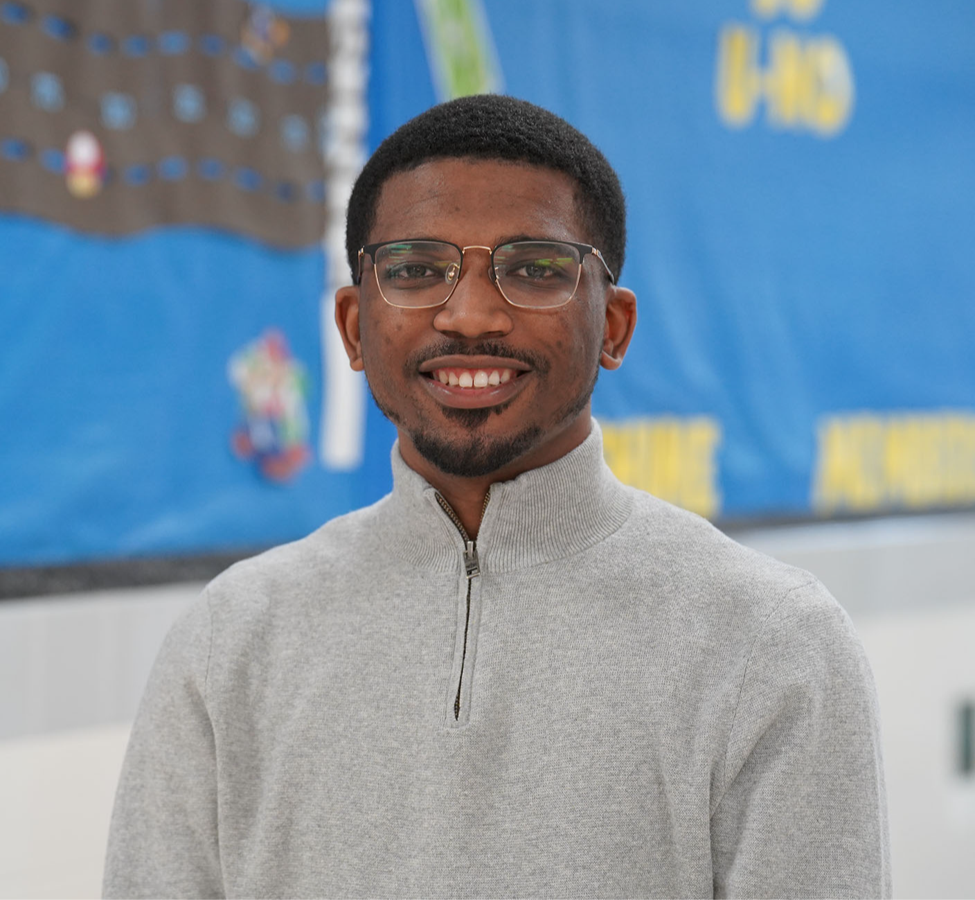 African American man wearing a gray sweater in a hallway