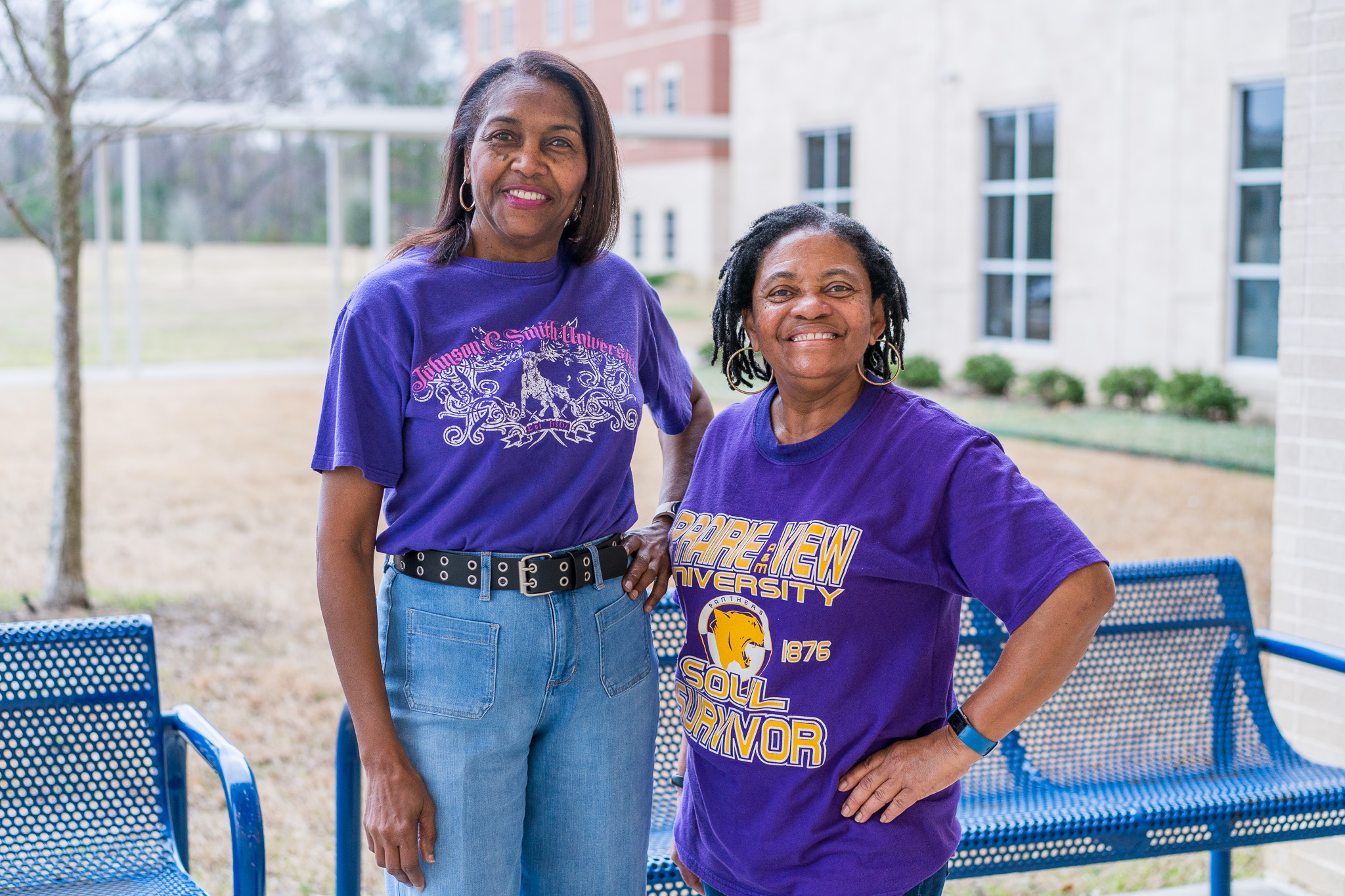 two women stand next to each other wearing purple college shirts