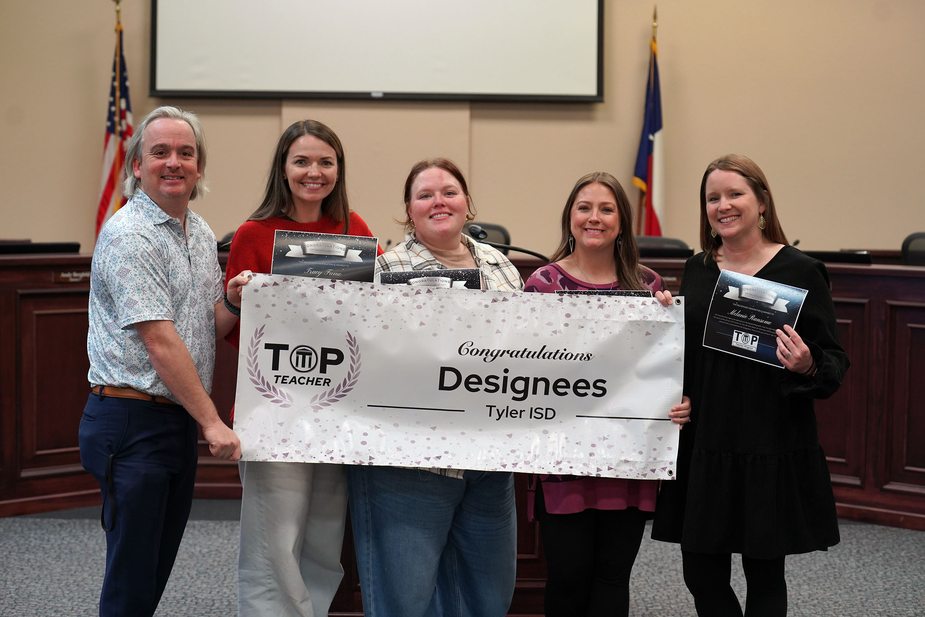 group of adults holding a TOP Teacher designee banner