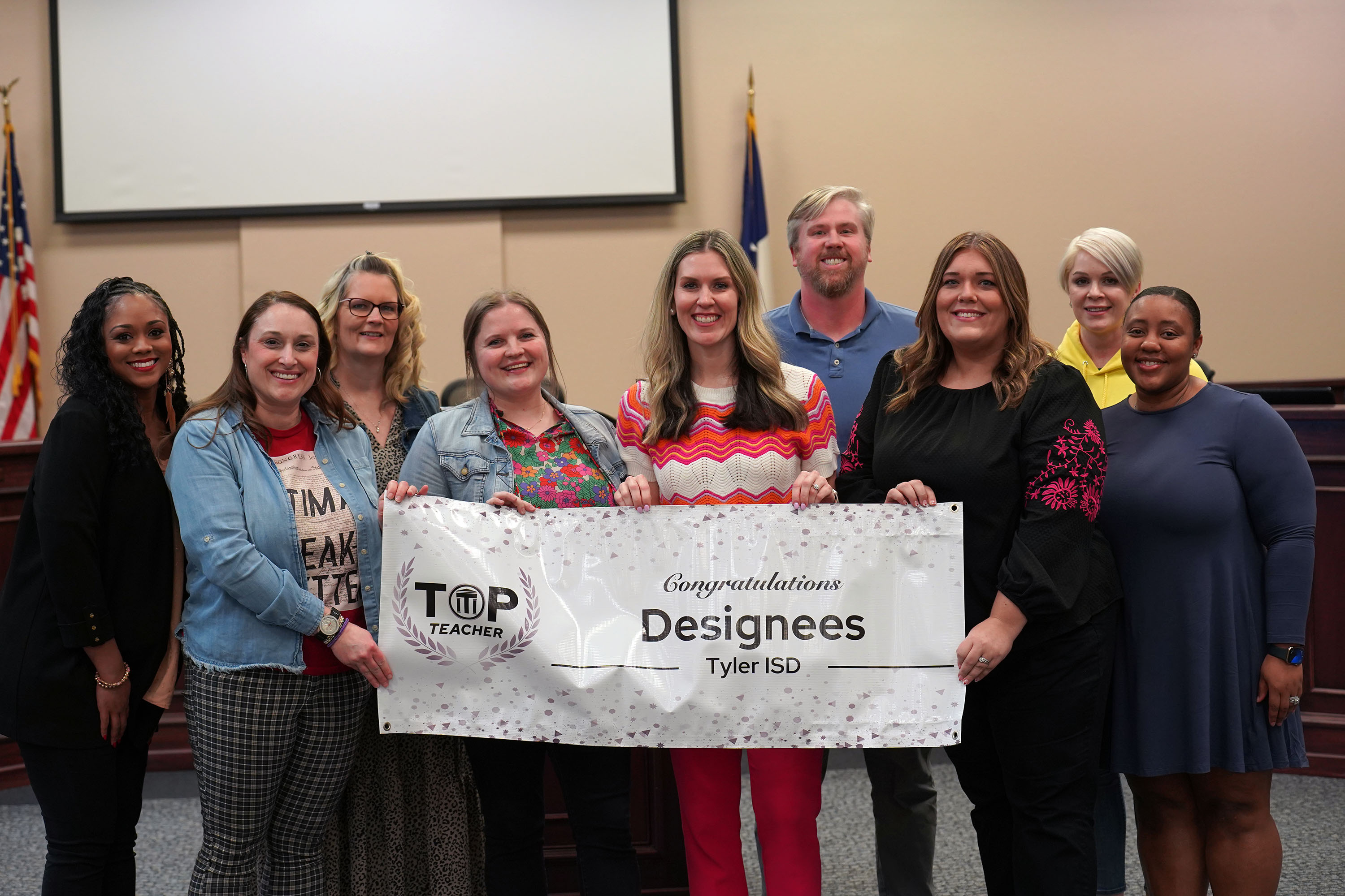 group of adults holding a TOP Teacher designee banner