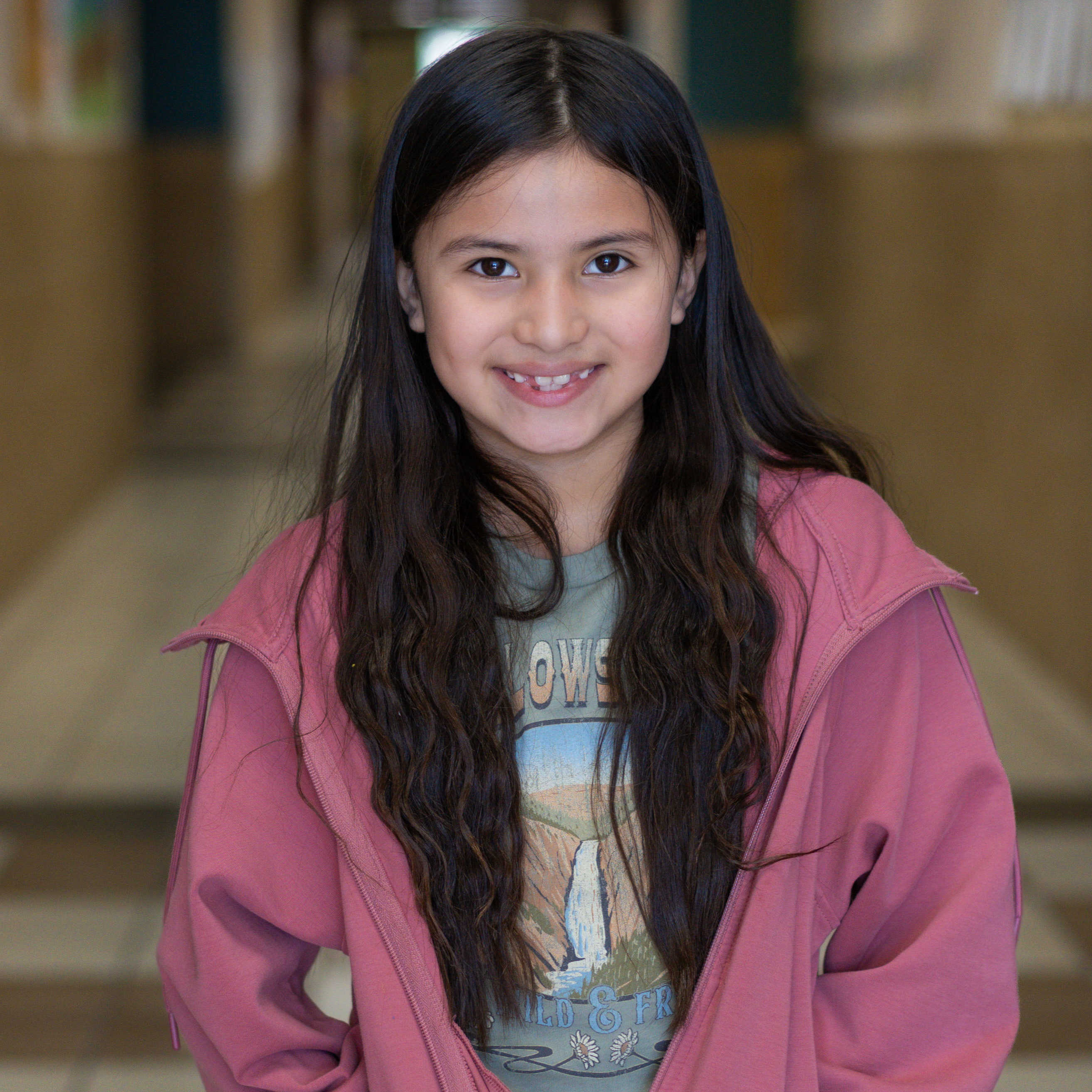 elementary age girl with long dark hair wearing a pink jacket