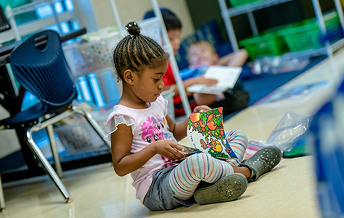African American female child sitting on the floor reading a book