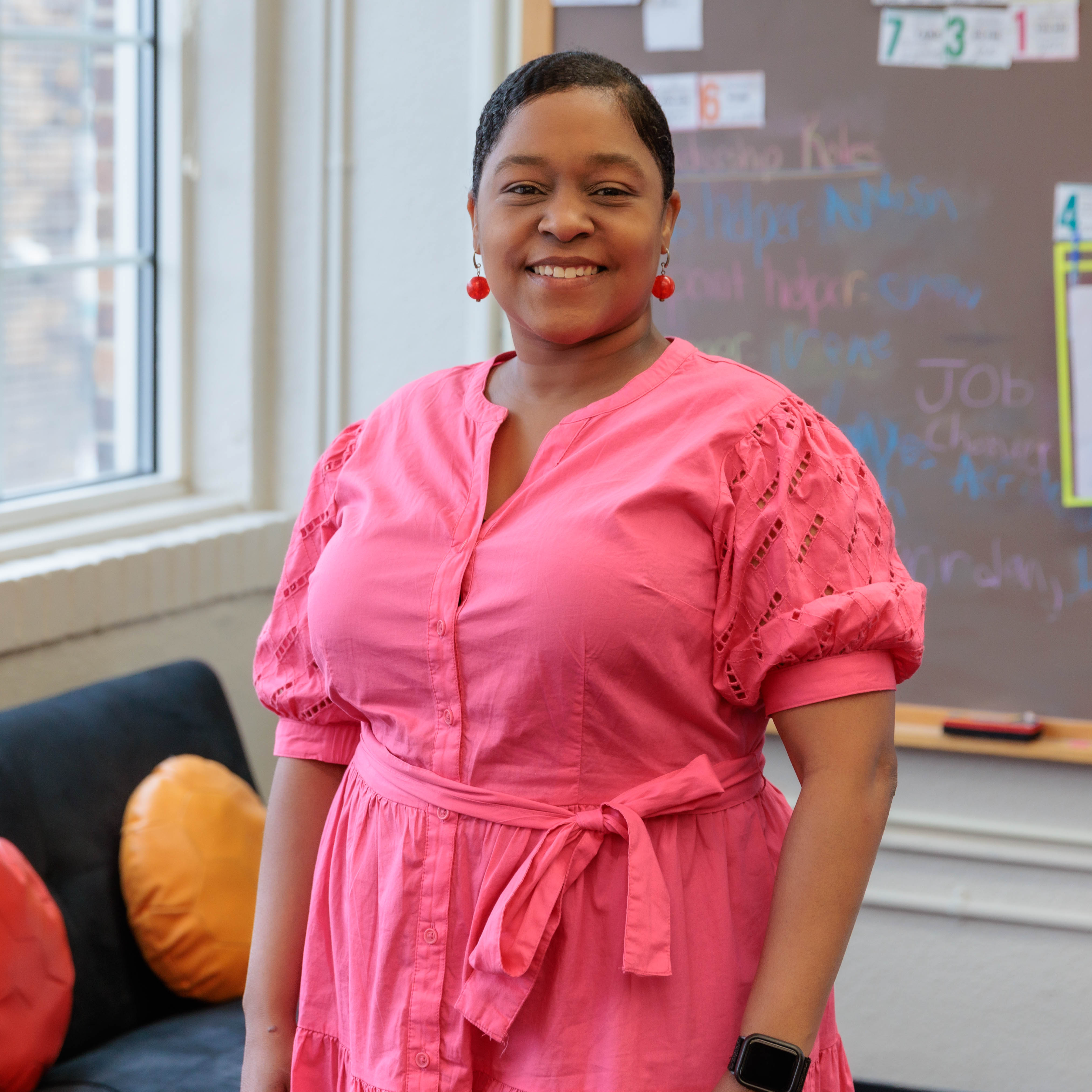 African American woman wearing a pink dress standing in a classroom