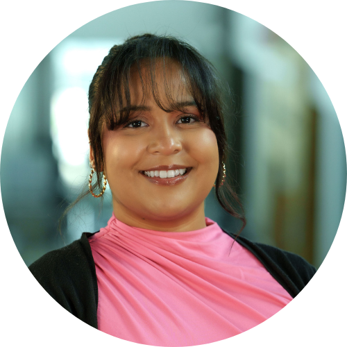 woman with dark hair wearing a pink shirt and black cardigan