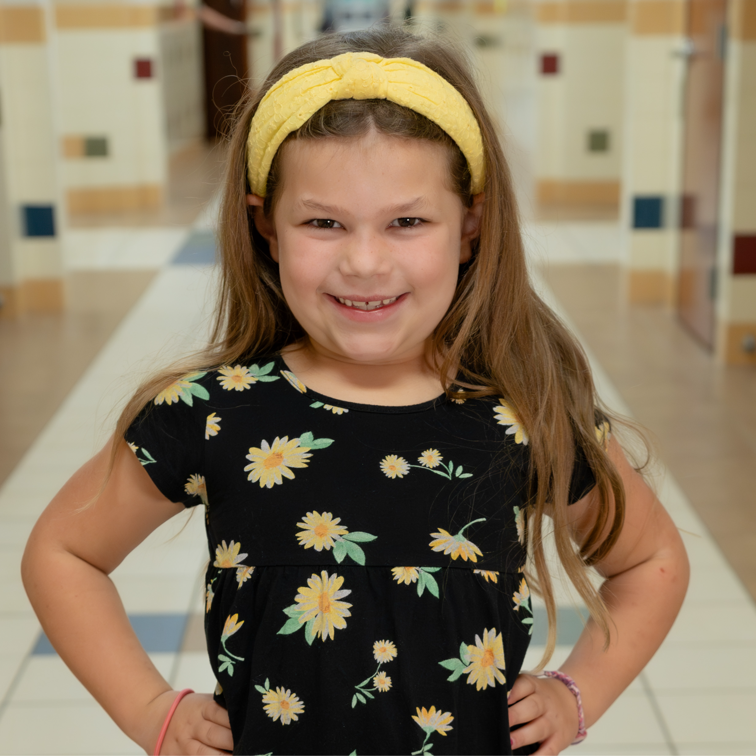 elementary age girl wearing a sunflower dress and yellow headband