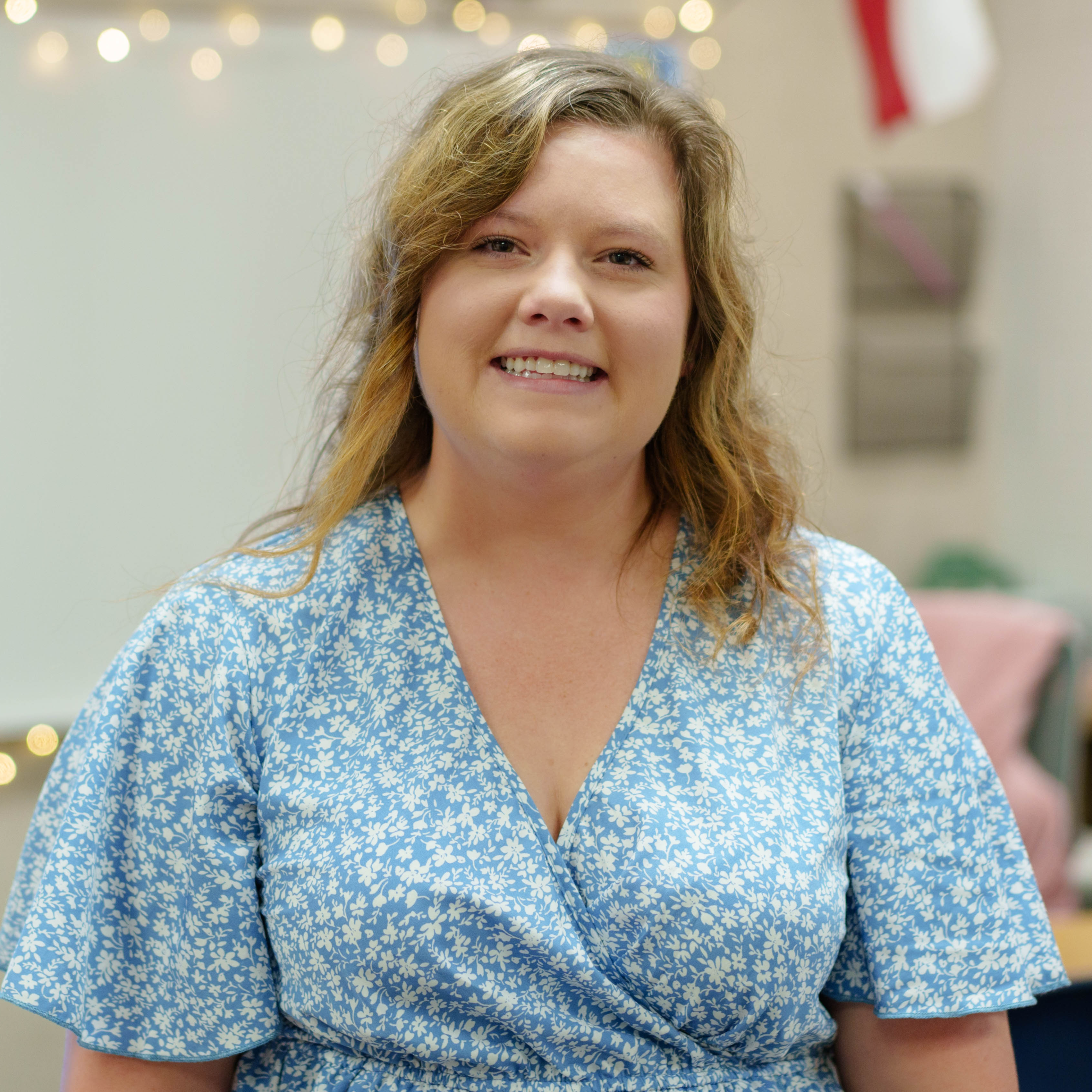 woman wearing a blue and white floral top standing in a classroom