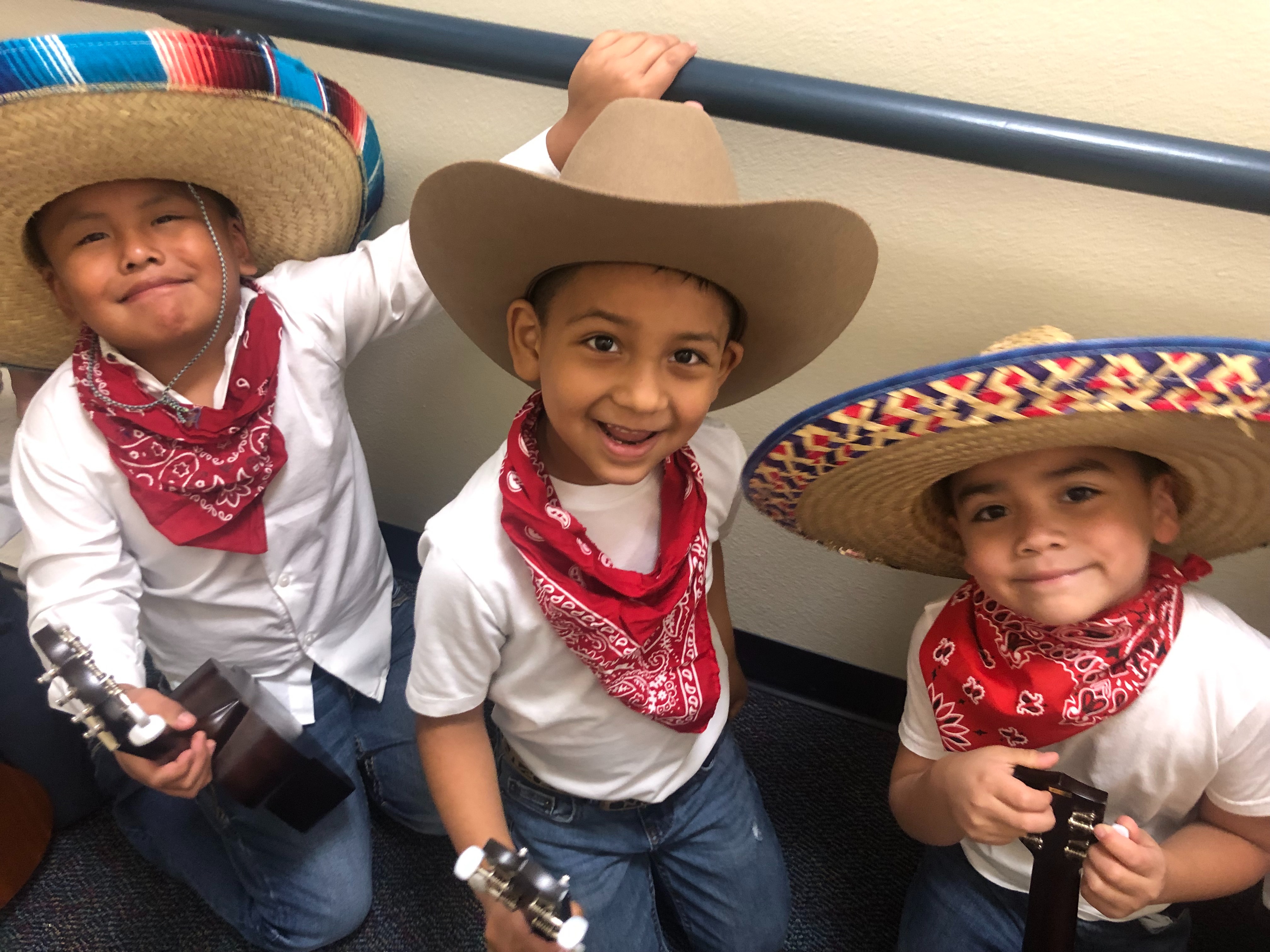 three elementary age boys wearing white t-shirts, red bandanas, and Mexican hats