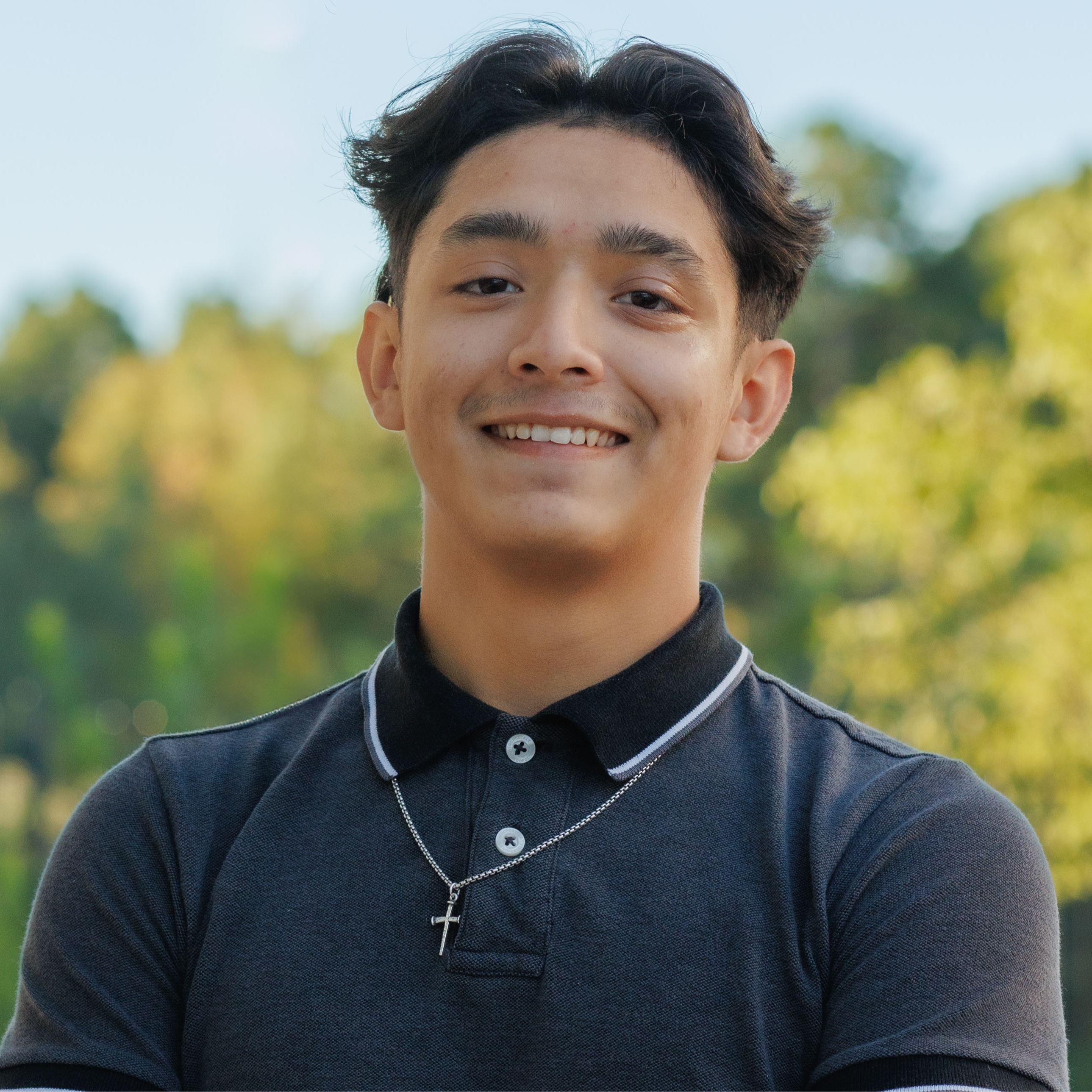 high school boy wearing gray polo and cross necklace